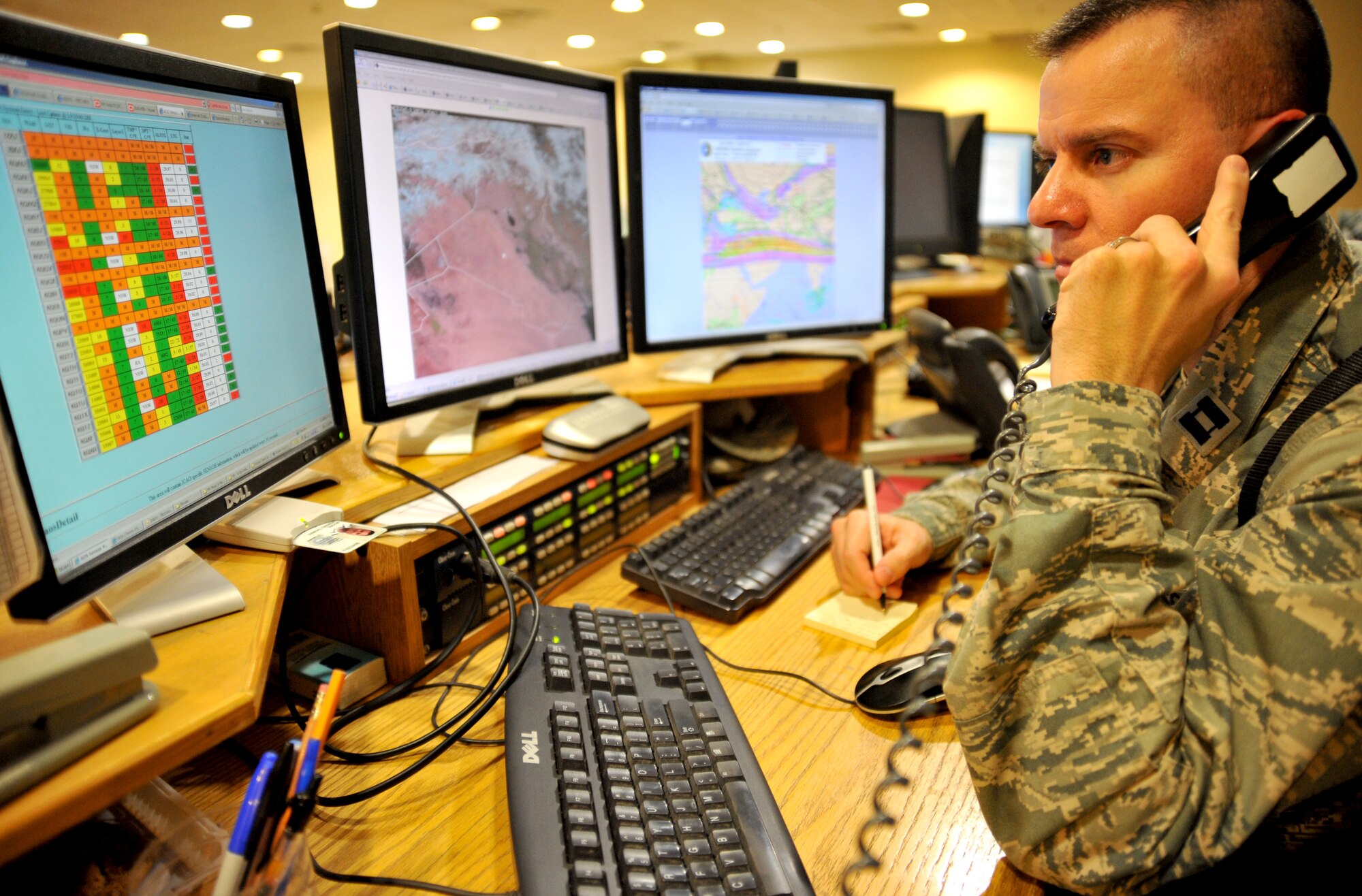 Capt. Howard Moore, U.S. Forces-Iraq Joint Operations Center staff weather officer, gathers updated forecast information from a fellow battlefield weather Airman Feb. 14, 2011, at Camp Victory, Iraq. (U.S. Air Force photo by Senior Airman Andrew Lee/Released)