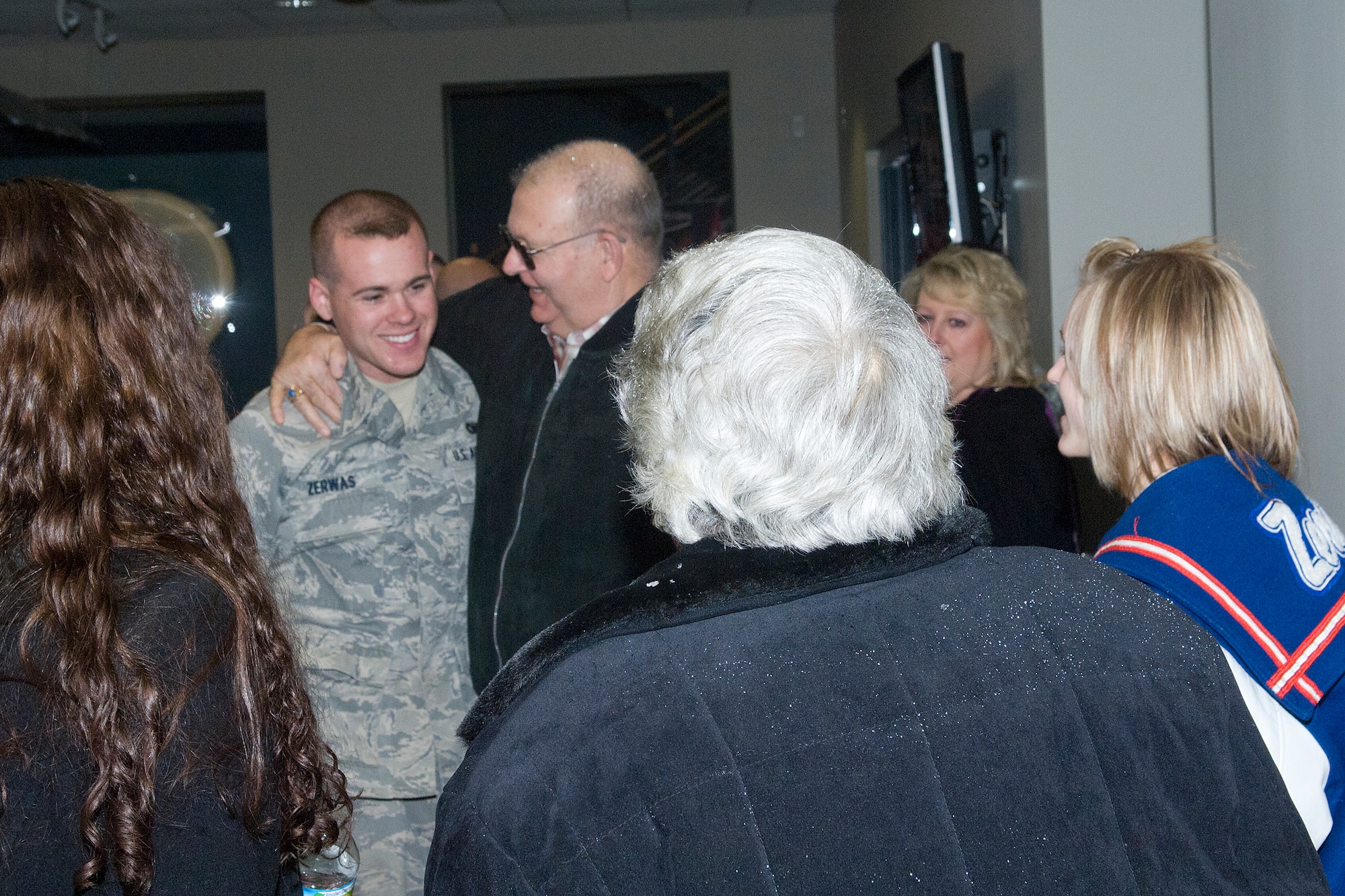 Senior Airman tony Zerwas (center) gets a hug from his grandfather, Joe Zerwas and is surrounded by his parents, siblings and many others as fifteen members of the 133rd Security Forces Squadron return from Iraq on Feb. 20, 2011 at the St. Paul Air National Guard Base. This was the second group of fifteen returning from a six-month deployment to Iraq in support of Operation New Dawn. The Airmen handled law enforcement duties and installation security for U.S. and host nation forces at the air base located at the Baghdad International Airport. USAF official photo by Senior Master Sgt. Mark Moss