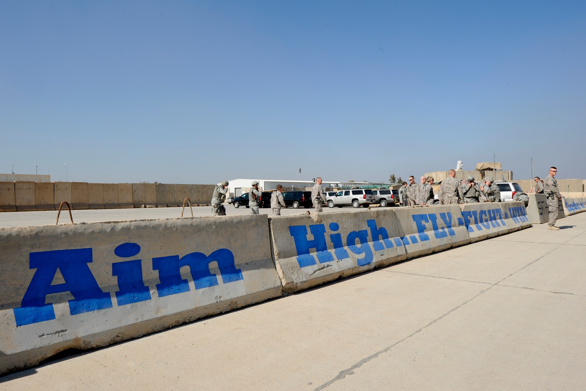 BAGHDAD -- Airmen wait for their plane to arrive next to the new flightline mural on Sather Air Base Feb. 19. The mural was the idea of Brig. Gen. Anthony Rock, the 321st Air Expeditionary Wing commander and Iraq Training and Advisory Mission – Air director, to improve the aesthetics of the area and promote teamwork.  (U.S. Air Force photo by Staff Sgt. Levi Riendeau)
