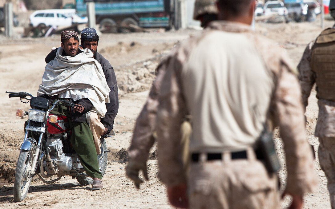 Locals of Garmsir district, Helmand province, Afghanistan, watch a group of US diplomats walk to the Garmsir District Center with a security entourage of Marines, Afghan National Army soldiers and Afghan National police, Feb. 21, to participate in a security and stability shura with Afghan officials. The US diplomats included Karl W. Eikenberry, the US ambassador to Afghanistan, and Senators Bob Corker, Tennesee; Bernie Sanders, Vermont; Joe Manchin, West Virginia; and Christopher Coons, Delaware. Afghan representatives included Mir Hamza, the national director of security; Gulab Mangal, the provincial governor of Helmand province; Omar Jahn, the local Aghan National Police chief; and Lt. Col. Hezbollah, the commanding officer of the local Afghan National Army kandak. Col. David Furness, the commanding officer of Regimental Combat Team 1, and Lt. Col. Matthew Reid, the commanding officer of 2nd Battalion, 1st Marine Regiment, also attended