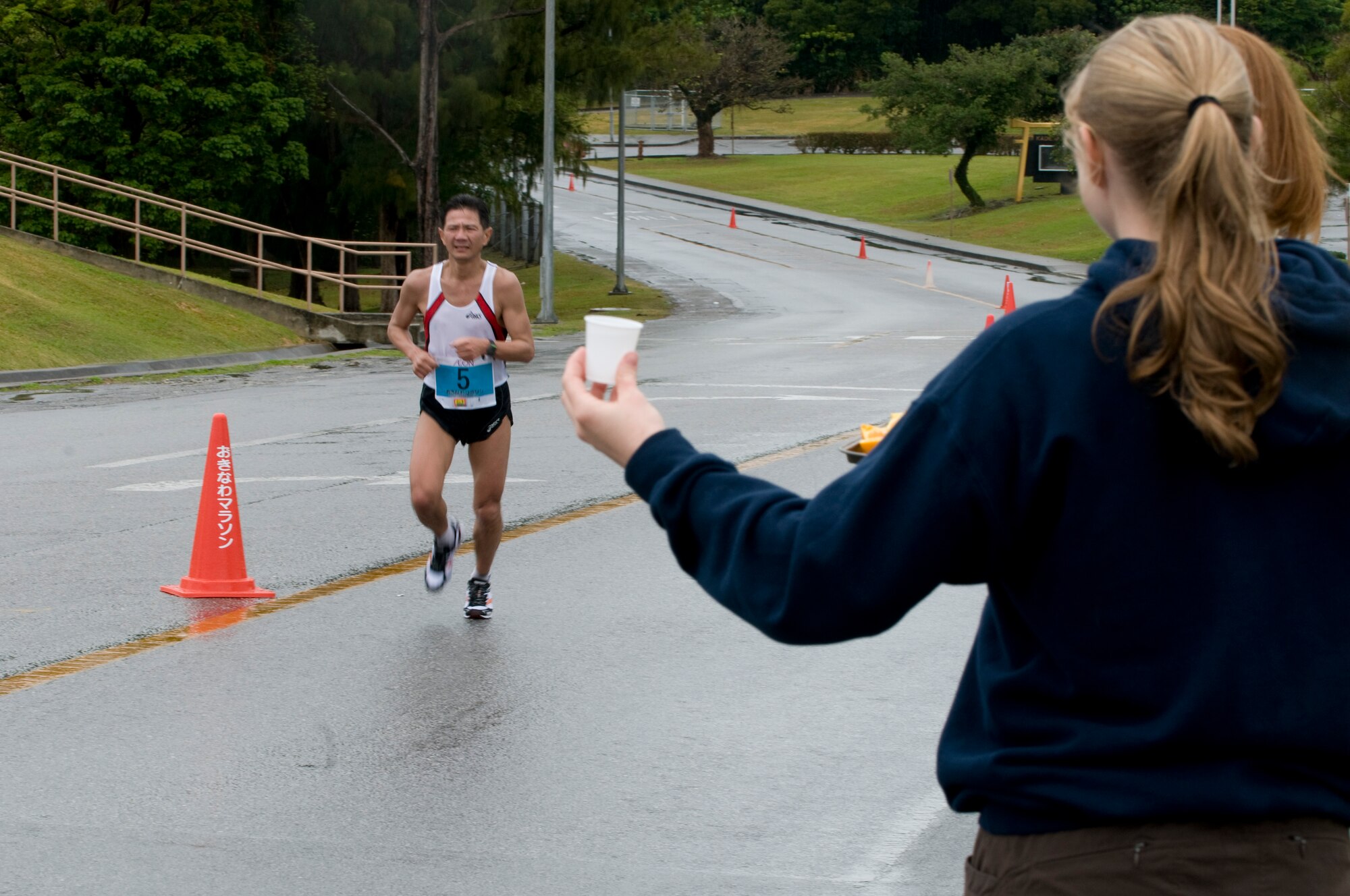A volunteer holds out water for a runner during the 2011 Okinawa Marathon near Kadena’s Gate 5, Feb. 20. The marathon went through a 1.5 mile stretch of Kadena and service members and their families participated in the marathon by either running the marathon or by simply passing out water and fruit to the runners. (U.S. Air Force photo/ Brooke P. Beers)