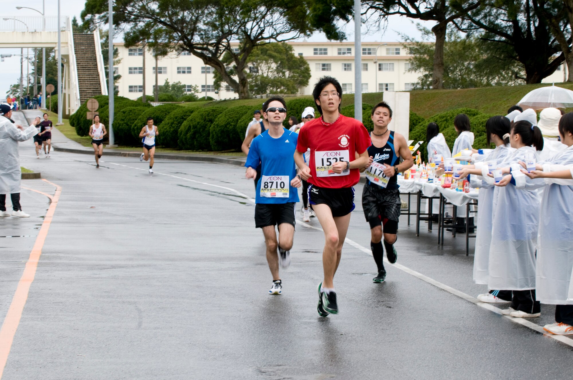 Runners participating in the 2011 Okinawa Marathon pass by a group of volunteers stationed along the marathon route by Kadena’s Gate 5, Feb. 20. Runners from the local community as well as Kadena service members participated in the 26.2 mile journey through nine different cities, towns and villages on the island, including the roughly 1.5 mile portion from Kadena’s Gate 2 to Gate 5. (U.S. Air Force photo/ Brooke P. Beers)