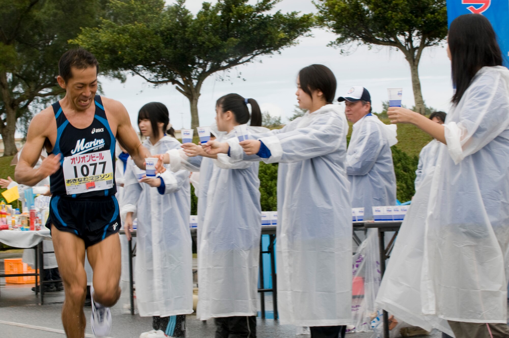 A runner in the 2011 Okinawa Marathon takes a cup of water from volunteers stationed along the marathon route through Kadena, Feb. 20. Team Kadena volunteers offered encouragement and refreshments along the roughly 1.5 mile long Kadena portion of the 26.2 mile marathon. (U.S. Air Force photo/ Brooke P. Beers)