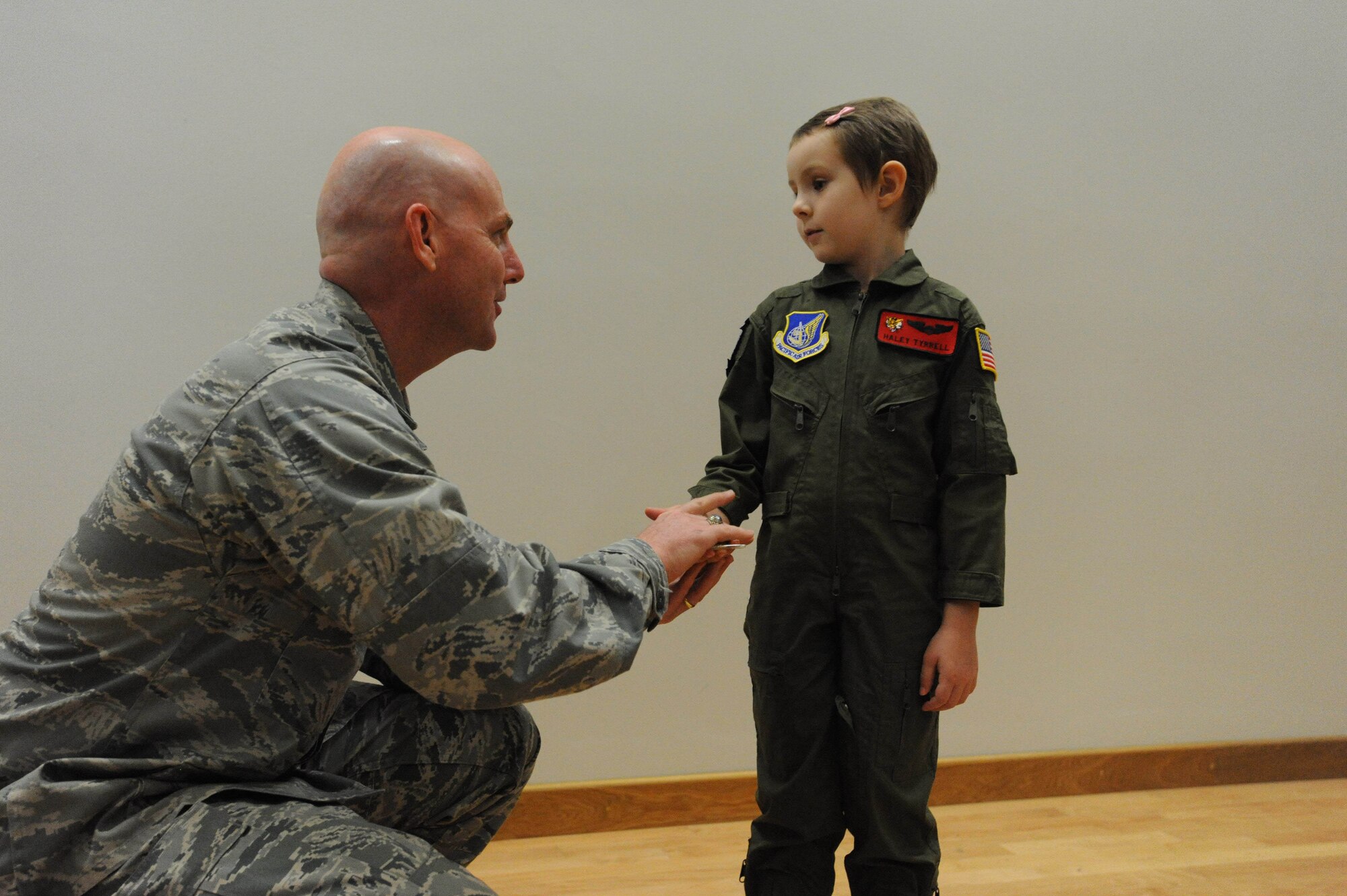 Col. Sam Barrett, 15th Wing commaner, presents a coin Feb. 18 to Haley Tyrrell after her "Pilot for a Day" tour on Joint Base Pearl Harbor Hickam, Hawaii. The goal of the program is to benefit children and their families in the local community who have catastrophic illnesses. Haley recently been declared cancer free after recovering from a cancerous brain tumor she was diagnosed with nearly two years ago. (U.S. Air Force photo/Staff Sgt. Nathan Allen)