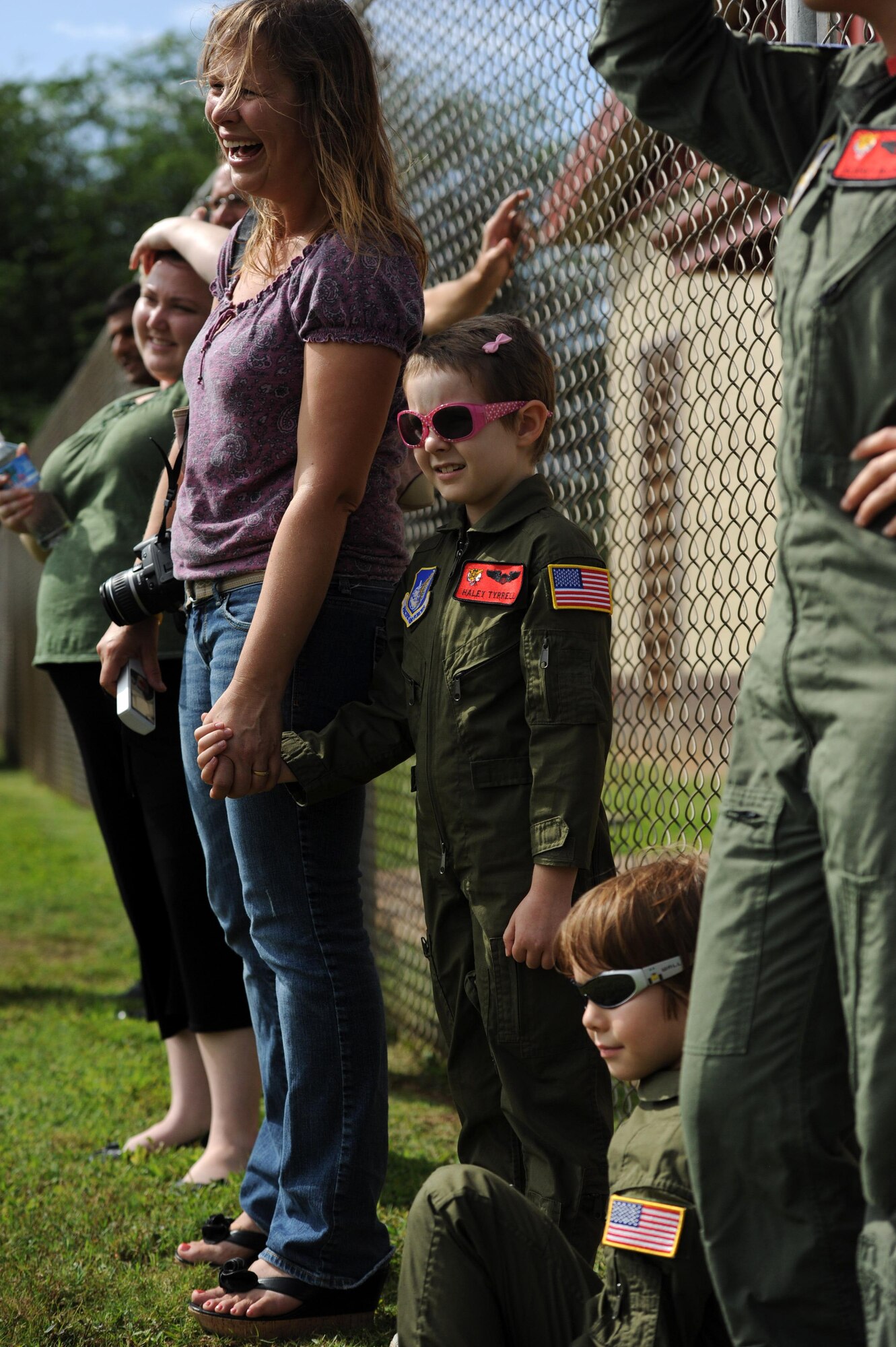 Haley Tyrrell (center) stands between her mother, Wendy Cockshell and her brother, Zachary Tyrrell while watching a military working dog demonstration Feb. 18 at the kennels during a "Pilot for a Day" tour on Joint Base Pearl Harbor Hickam, Hawaii. The goal of the program is to benefit children and their families in the local community who have catastrophic illnesses. Haley recently been declared cancer free after recovering from a cancerous brain tumor she was diagnosed with nearly two years ago. (U.S. Air Force photo/Staff Sgt. Nathan Allen)