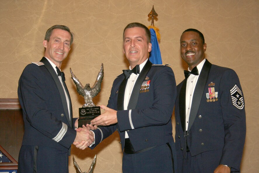 Maj. James Dickey, center, accepts the 301st Fighter Wing's 2010 Company Grade Officer of the Year Award on behalf of Capt. Charles Delongchamp III, who was deployed the night of Feb. 19 at the wing's annual awards banquet, held at the Fort Worth, Texas, Hilton.  Presenting the award is Brig. Gen. Ronald B. Miller, 301 FW commander, left; and Command Chief Master Sgt. Elroy Combs, Jr.  Captain Delongchamp and Major Dickey are from the 301st Logistics Readiness Squadron.  The wing's Chiefs' Group planned and carried out the event, which saw six award winners cross the stage.  (U.S. Air Force photo/Staff Sgt. Chris Bolen)