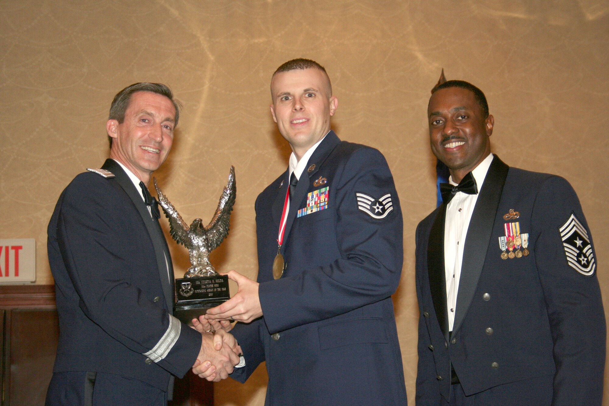 Staff Sgt. Jonathan M. Gibson, center,  is presented the 301st Fighter Wing's 2010 NCO of the Year Award at the wing's annual awards banquet, Feb. 19, 2011, at the Fort Worth, Texas, Hilton.  Presenting the award is Brig. Gen. Ronald B. Miller, left, 301 FW commander; and Command Chief Master Sgt. Elroy Combs, Jr.  Sergeant Gibson is a reservist from the 301st Operations Support Flight and was one of six award recipients honored at the event.  (U.S. Air Force photo/Staff Sgt. Chris Bolen)
