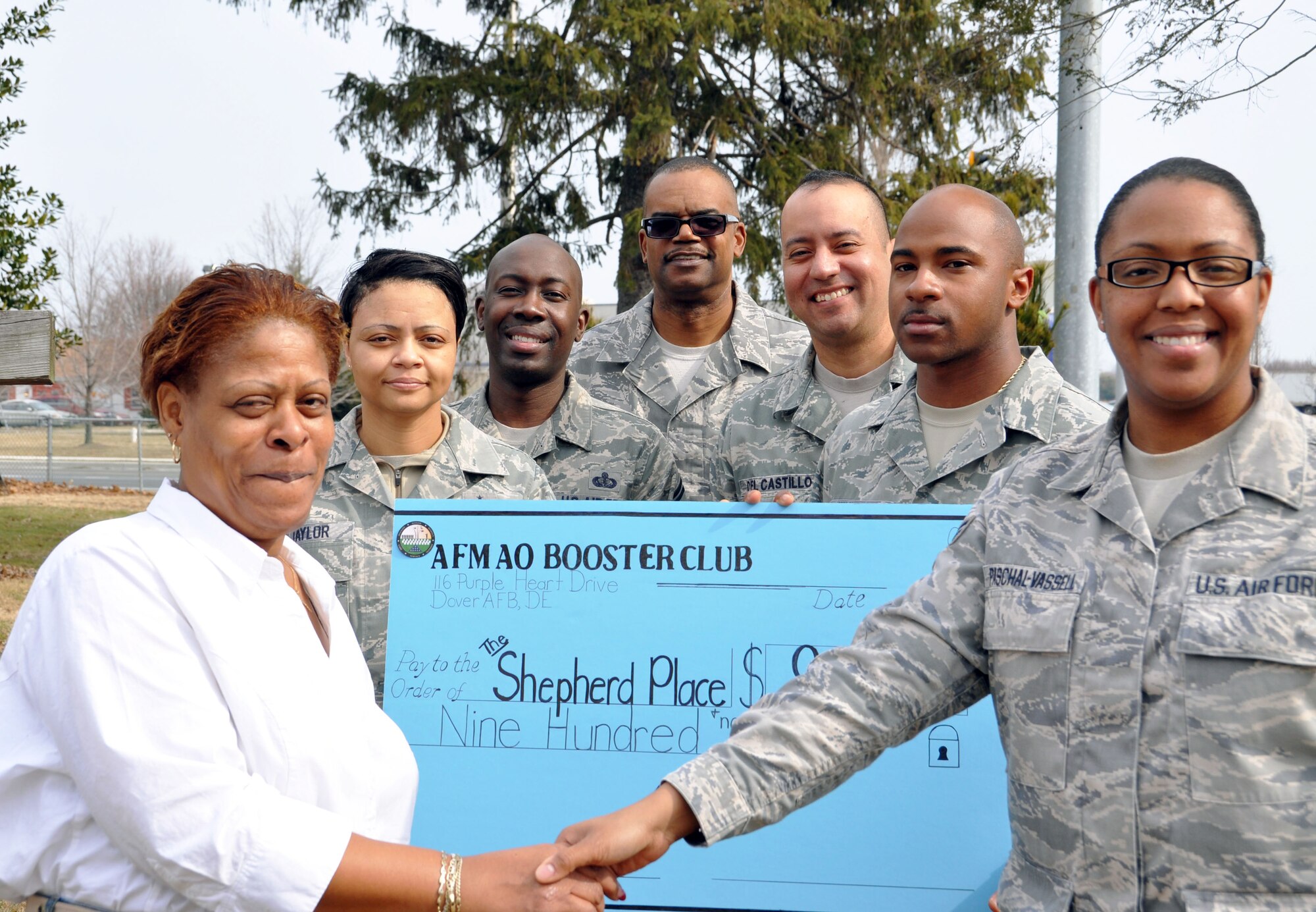 Saydonyia Campbell, (left) a shelter manager at The Shepherd Place, accepts a donation on behalf of the Air Force Mortuary Affairs Operations booster club. The booster club raised $900 for the shelter. (U.S. Air Force photo/Capt. Raymond M. Maguire)