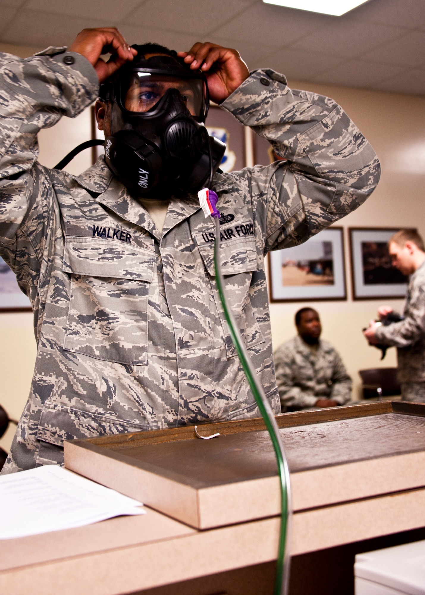 Staff Sgt. Terence Walker, 96th Force Support Squadron, adjusts the straps on his mask prior to starting the gas mask fit test while a 96th Aerospace Medical Squadron Airman explains mask procedures to the next Airman to undergo the test.  The testing took place Feb. 18 prior to Eglin’s phase two exercise Feb. 22-25.  The test is to ensure personnel are fitted to the proper size mask and to build confidence in its performance and use, according to 2nd Lt. Lindsay M. Kotouch, 96th Aerospace Medical Squadron.  The exercises used alter the seal as facial movements occur and ensure the mask to face seal is not broken and won't allow contamination into the mask.  (U.S. Air Force photo/Samuel King Jr.)