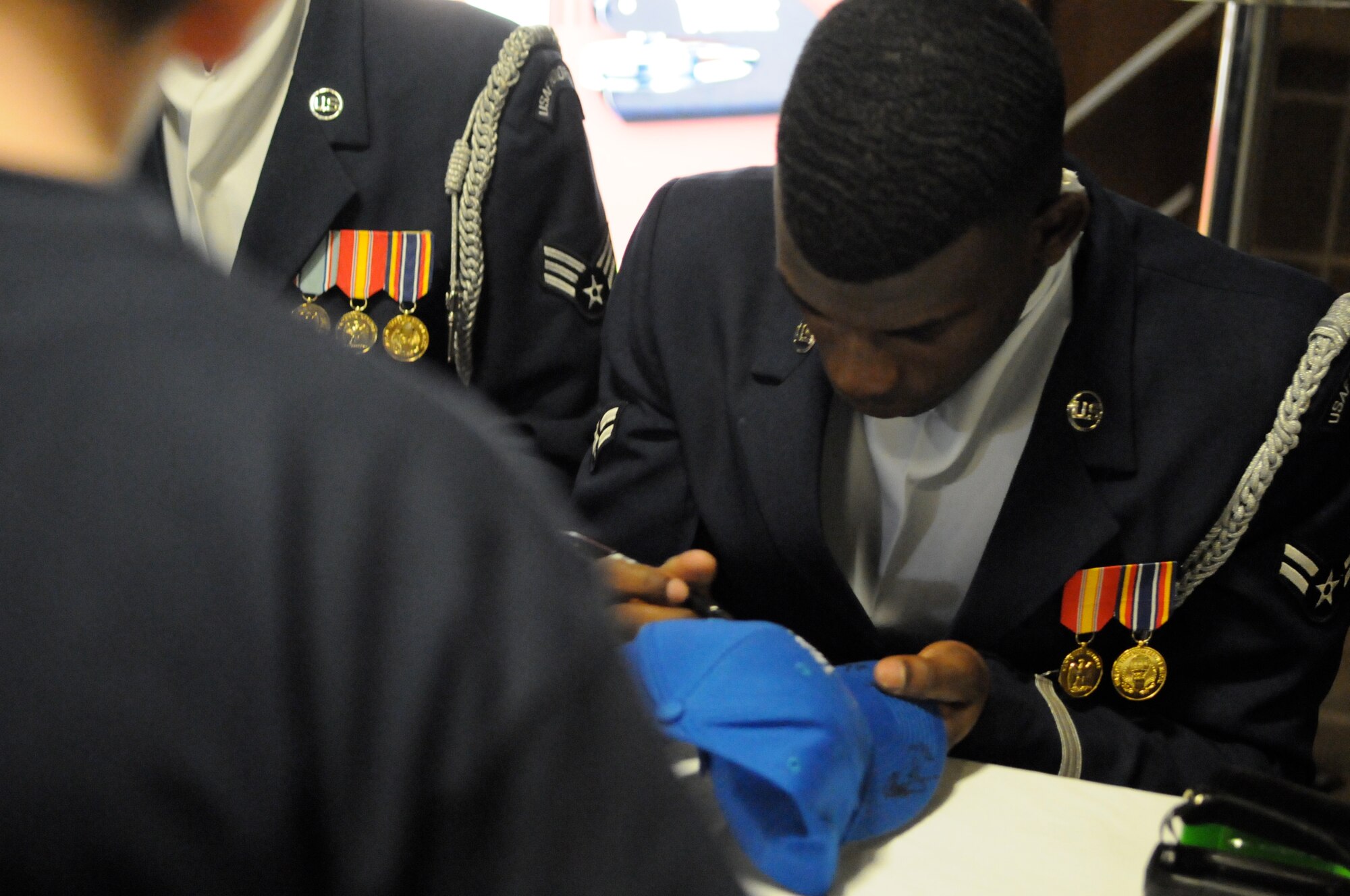Airman 1st Class Billy Degraffenreid Jr., member of The U.S. Air Force Honor Guard drill team, signs his autograph Feb. 15 at the Oklahoma City Thunder stadium during military appreciation night. The drill team performed the halftime show during the game, representing service members for military appreciation night. (U.S. Air Force photo by Airman 1st Class Tabitha N. Haynes)
