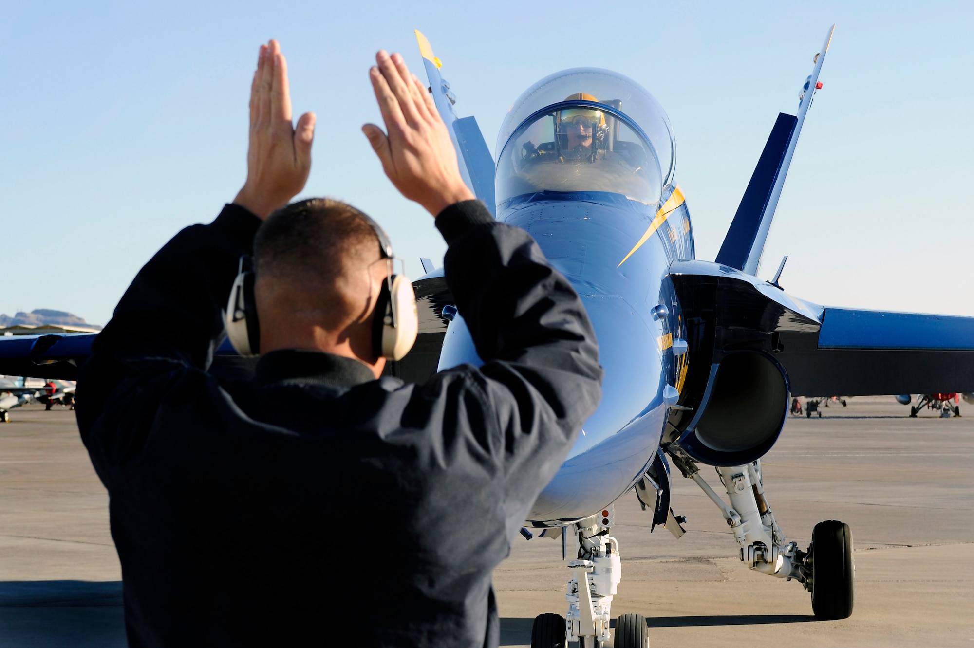 Staff Sgt. Brian Emerson marshals in U.S. Navy Blue Angels #5 Lt. Ben Walborn and #4 Rob Kurrle as they arrive to the Thunderbird hangar at Nellis Air Force Base, Nev., Feb. 23, 2011.
(U.S. Air Force Photo/Staff Sgt. Richard Rose Jr.)