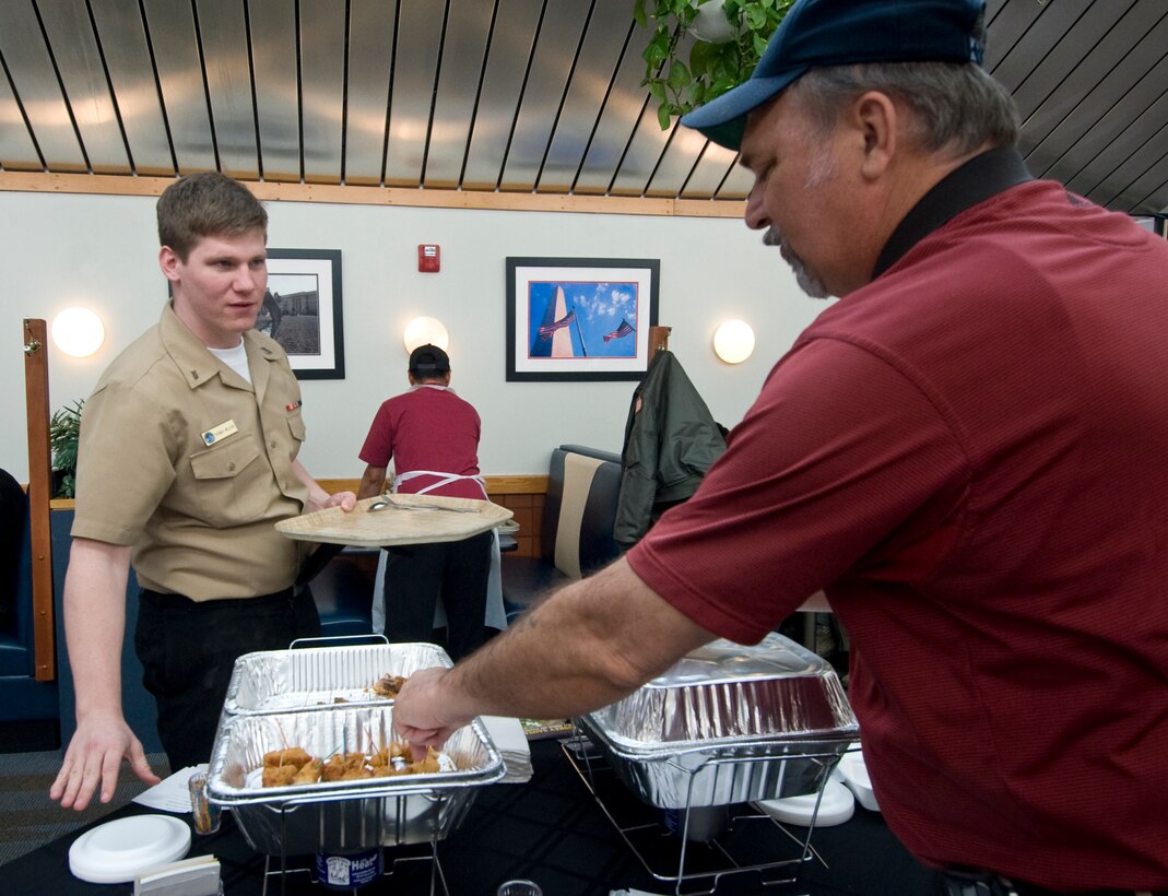 Navy Seaman, Thomas Wilson, left, an information systems technician assigned to Naval Communication Security Material System, receives food samples from Tom Kuch, a military food sales manager, during a food fair at the Freedom Hall Dining facility Feb. 22. The dining facility sponsors periodic food fairs to provide Joint Base Andrews members with a variety of alternative food choices to add to the current menu. (U.S. Air Force photo/Bobby Jones)