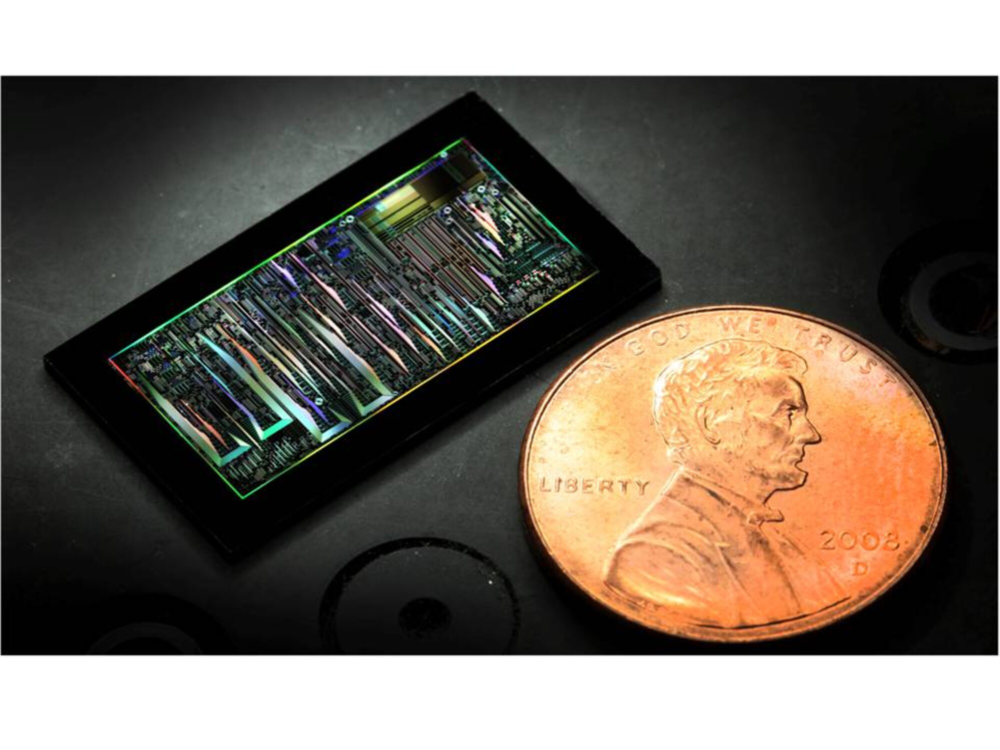 A dark-field optical image of a silicon photonic chip is shown in
comparison to the size of a penny.(Credit: Elijah Douglas Christenson)

