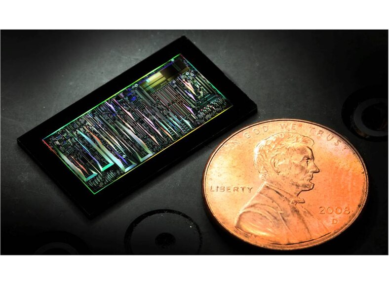 A dark-field optical image of a silicon photonic chip is shown in
comparison to the size of a penny.(Credit: Elijah Douglas Christenson)
