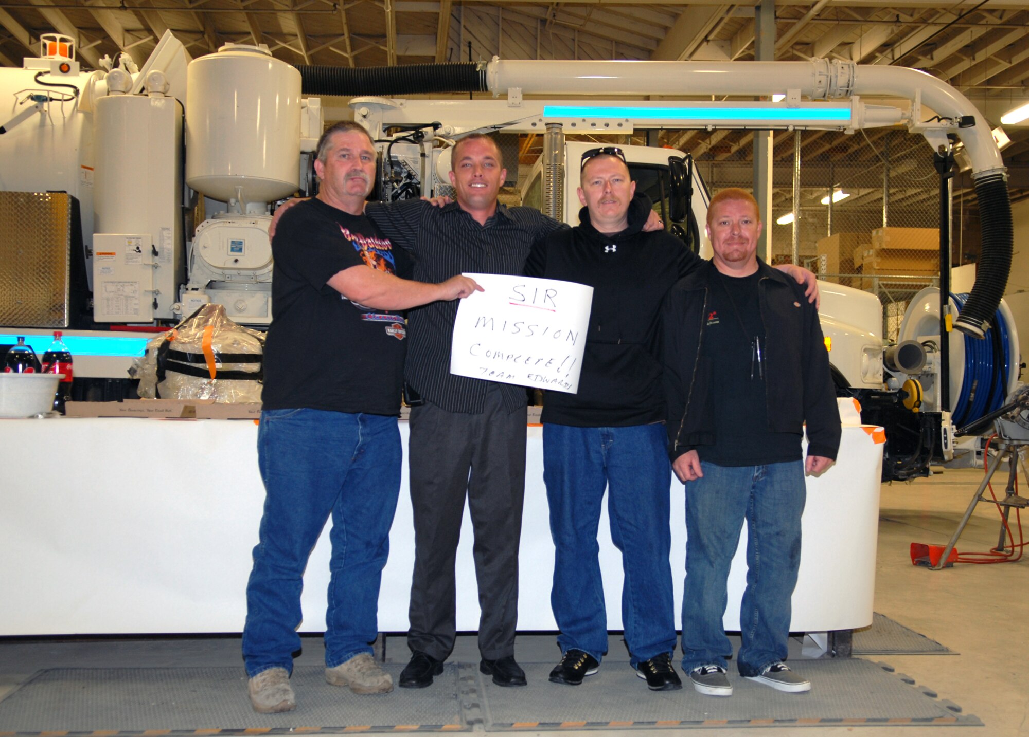 From left to right: Pete Neeley, Jose Rodriguez, Mike Warren and John Shartzer hold a sign that says, “Sir Mission Complete!! Team Edwards,” after the successful completion of their TDY to Kirtland Air Force Base, N.M. The four, all members of the 95th Civil Engineering Division, returned Feb. 18. They were called to Kirtland the weekend of Feb. 4 after the worst winter storm in more than 20 years ruptured several pipes around the base shutting down base facilities and family housing. (Air Force photo by Senior Airman William A. O'Brien)