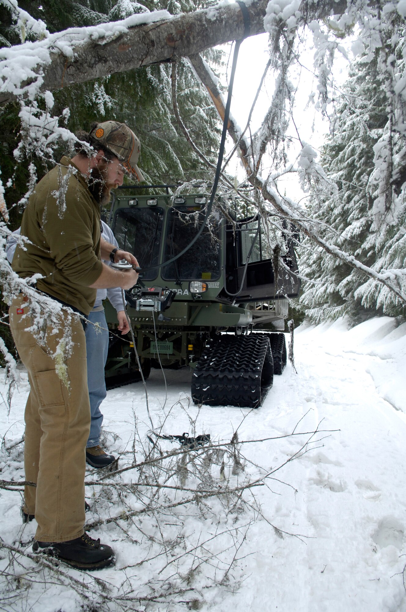 Todd Foster latches a harness to a tree blocking the path to a radio tower he and three transmission systems radio Airmen were on their way up to Feb. 16, 2011 at the Calispell Mountains in Spokane, Wash. Mr. Foster is a survival evasion resistance and escape specialist with the 336th training group. He and the communications Airmen were on their way up to the tower to clear snow and ice off of it. Clearing the tower enables vital radio communications for 336th Training Group and local law enforcement. These radio communications are used for rescue and training missions.  (U.S. Air Force photo/ Senior Airman Natasha E. Stannard)