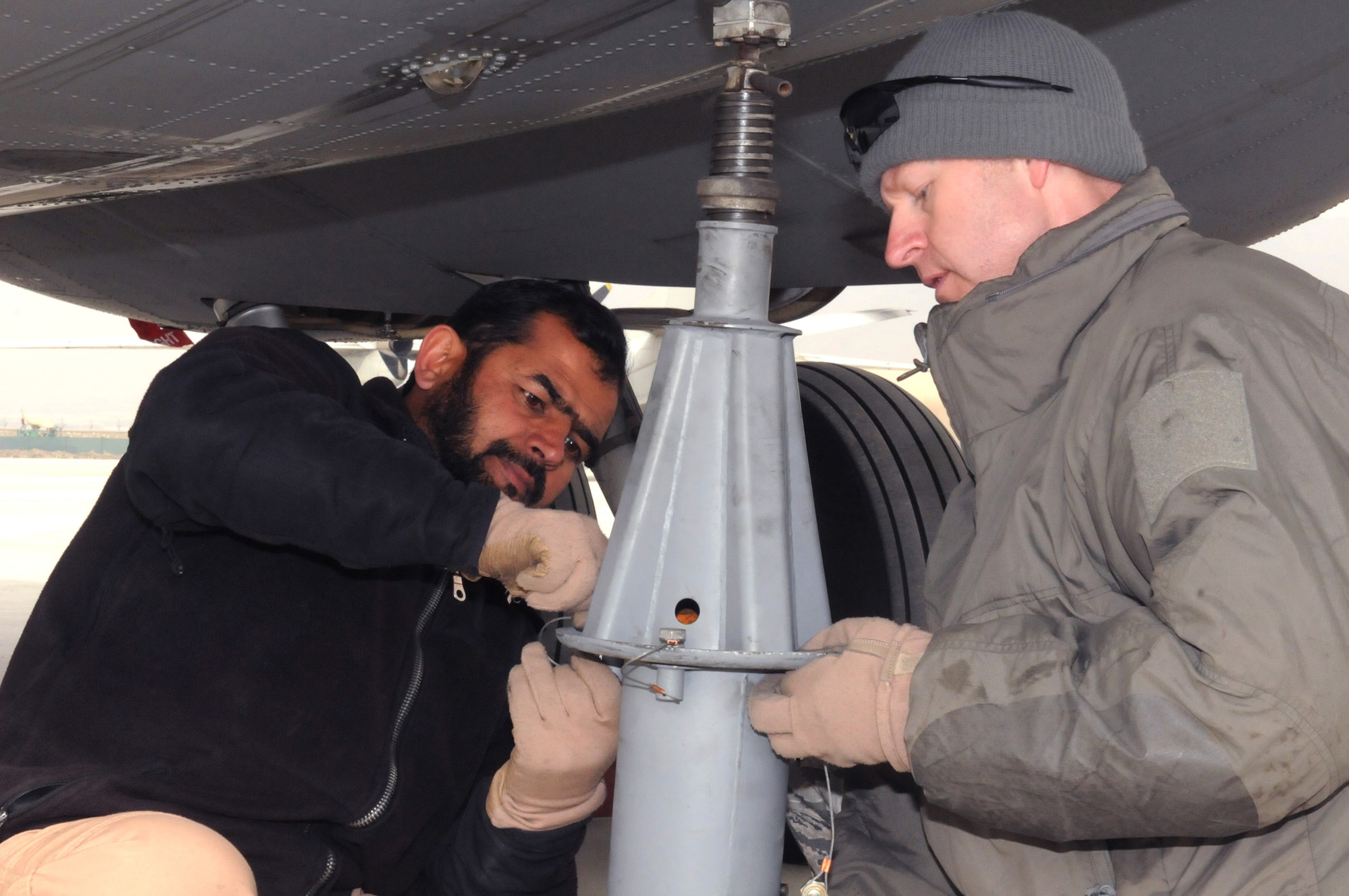 Master Sgt. Chris Neufeld helps an Afghan air force loadmaster-in-training apply a jack to a C-27 Spartan during an off-load mission at the Afghan air force base Feb. 21, 2011, in Kabul. Sergeant Nuefeld is a NATO Air Training Command-Afghanistan C-27 loadmaster adviser with the 538th Air Expeditionary Advisory Squadron. (U.S. Navy photo/Petty Officer 2nd Class Vladimir Potapenko) 