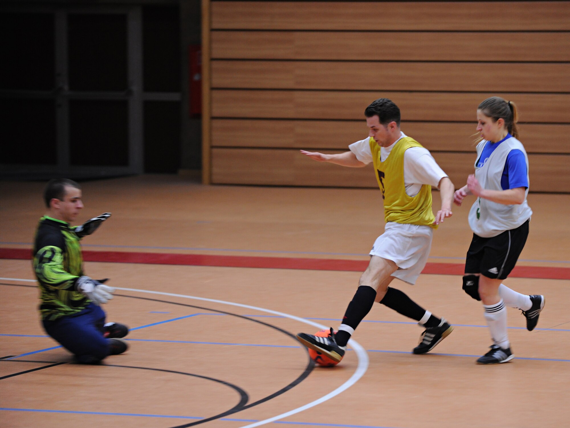 SPANGDAHLEM AIR BASE, Germany – Benjamin Carpenter, 81st Fighter Squadron, takes a shot on goal as Steven Kalkosen, goalie, and Tabitha Smith, far right, 606th Air Control Squadron, defend during the first game of the indoor soccer season Feb. 22 at the Skelton Memorial Fitness Center. The 81st FS team crushed the 606th ACS 13-1. (U.S. Air Force photo/Staff Sgt. Benjamin Wilson)
