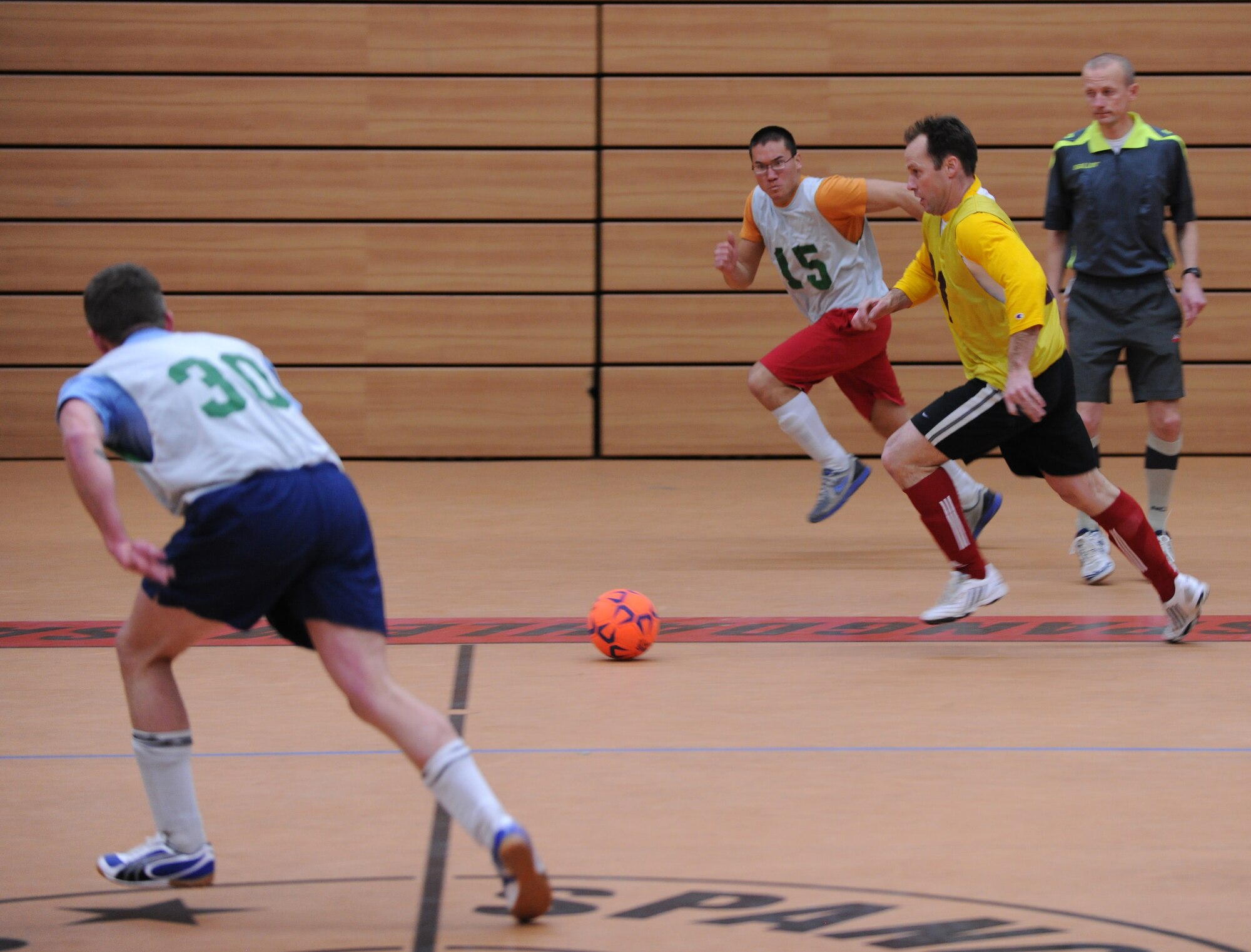 SPANGDAHLEM AIR BASE, Germany – John Liller, in yellow from the 81st Fighter Squadron, dribbles the ball through his opponents during the first game of the indoor soccer season Feb. 22 at the Skelton Memorial Fitness Center. The 81st FS team crushed the 606th Air Control Squadron team 13-1. (U.S. Air Force photo/Staff Sgt. Benjamin Wilson)