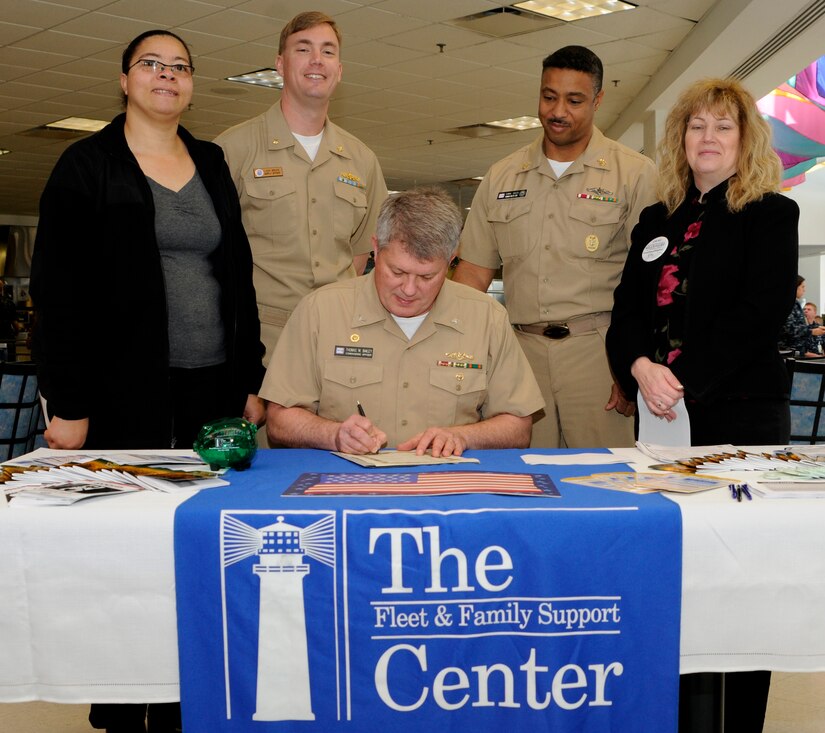 Capt. Thomas Bailey signs the proclamation for Military Saves Week as Donna Levy-Quinton (left), Lt. Cmdr. Mike Bruce, Master Chief Gamal Coles, and Melanie Brenham watch at the five-star galley at Joint Base Charleston-Weapons Station, Feb. 22.  Captain Bailey is the NNPTC commanding officer, Ms. Levy-Quinton is a Fleet and Family Support Center volunteer, Commander Bruce is the JB CHS - WS supply officer, Master Chief Coles is the NNPTC Command Master Chief and Ms. Brenham is a FFSC financial specialist. (U.S. Navy photo/Machinist’s Mate 3rd Class Brannon Deugan)