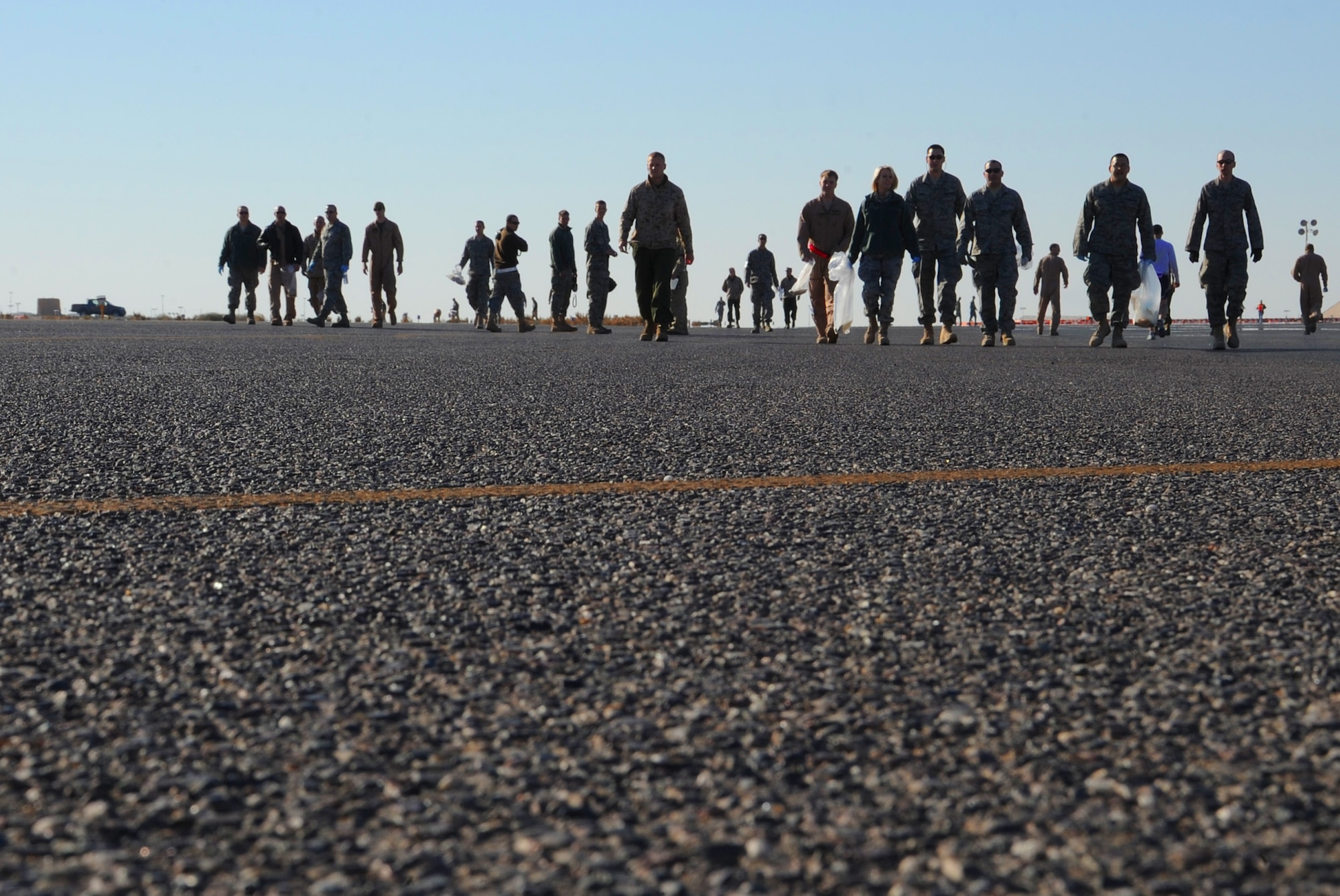 Airmen with the 386th Air Expeditionary Wing participate in the quarterly foreign object disposal walk on the flightline Feb. 19. A FOD walk is done to ensure that the flightline is free of any debris that may effect the safety of air transportation. (U.S. Air Force photo by Senior Airman Cynthia Spalding)