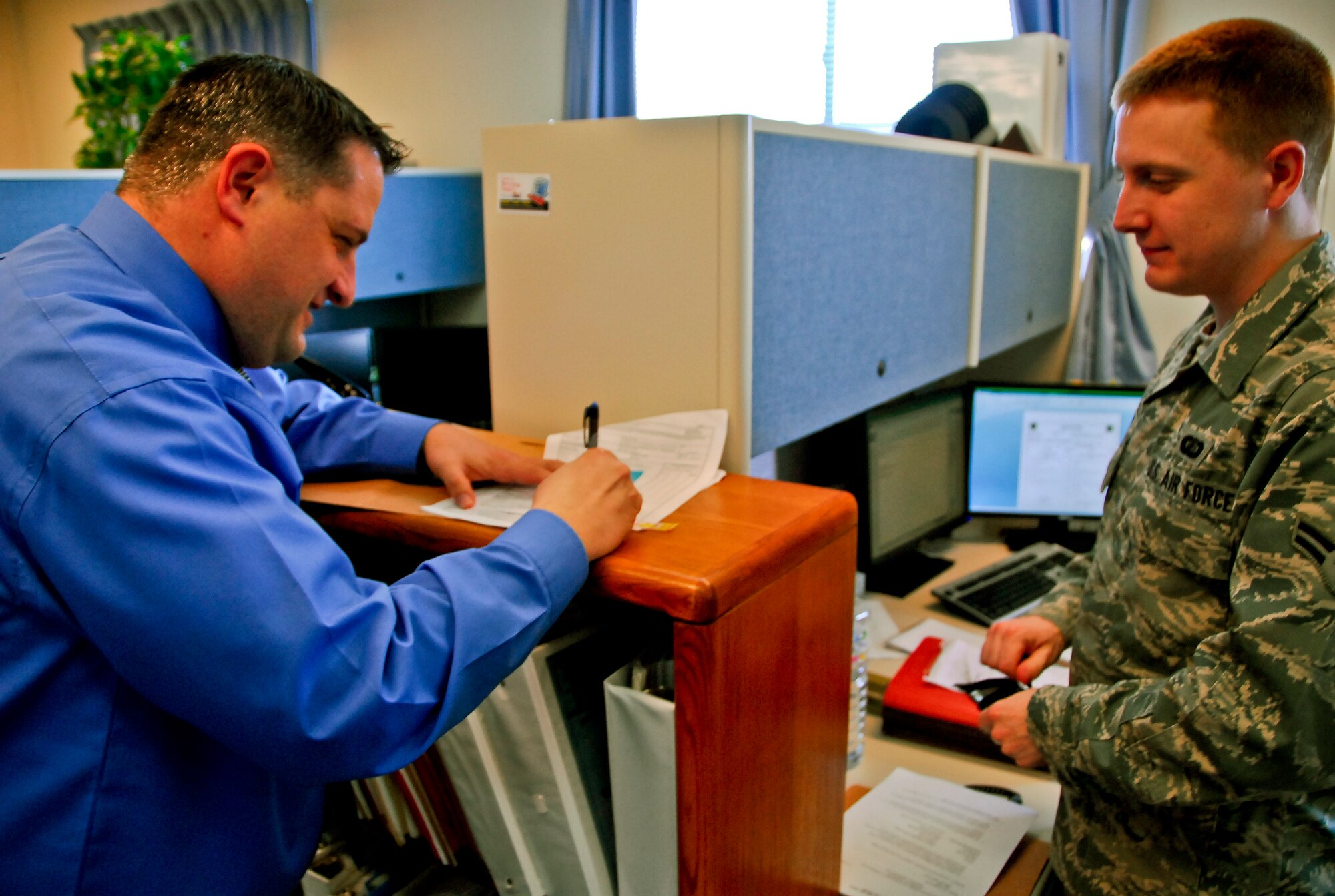Martin Hansen, 18th Contracting Squadron contracting officer, approves and signs a contractor request form from Airman 1st Class Scott Cole, 18th CONS contracting specialist, for a contractor conducting work on Kadena, Feb. 22. Mr. Hansen is the PACAF nominee for the 2011 Air Force Association Outstanding Civilian of the Year Program. (U.S. Air Force photo/ Airman 1st Class Maeson L. Elleman)