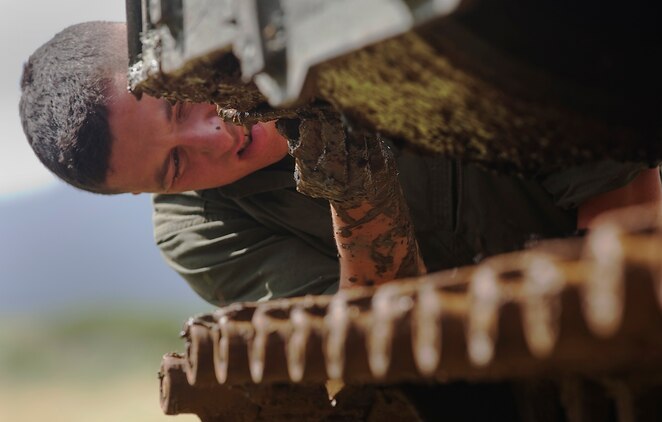 Lance Cpl. Michael Haus, an amphibious assault vehicle crewman with AAV Platoon, Combat Assault Company, 3rd Marine Regiment, picks debris off an AAV after it tore up invasive pickleweed in the Nuupia Ponds Wildlife Management Area during the 29th annual Mud Ops exercise on Marine Corps Base Hawaii, Feb. 23, 2011. The 29-year-long Mud Ops tradition partnered AAV Platoon Marines with the base Environmental Compliance and Protection Department to prepare the 517-acre area for the upcoming breeding season of the endangered Hawaiian stilt bird species, which lasts from March until September.