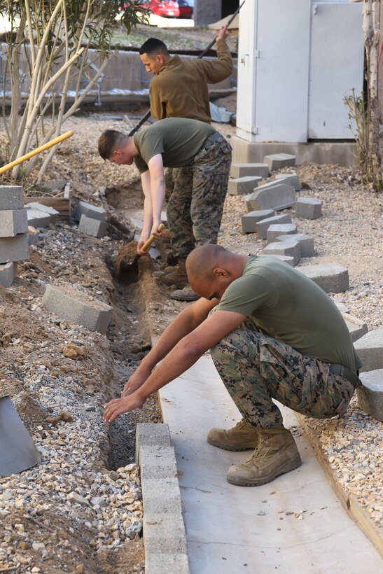 Marines dig along the side of the drainage and place dresser stones during a working party at the Headquarters Battalion barracks Feb. 24, 2011.