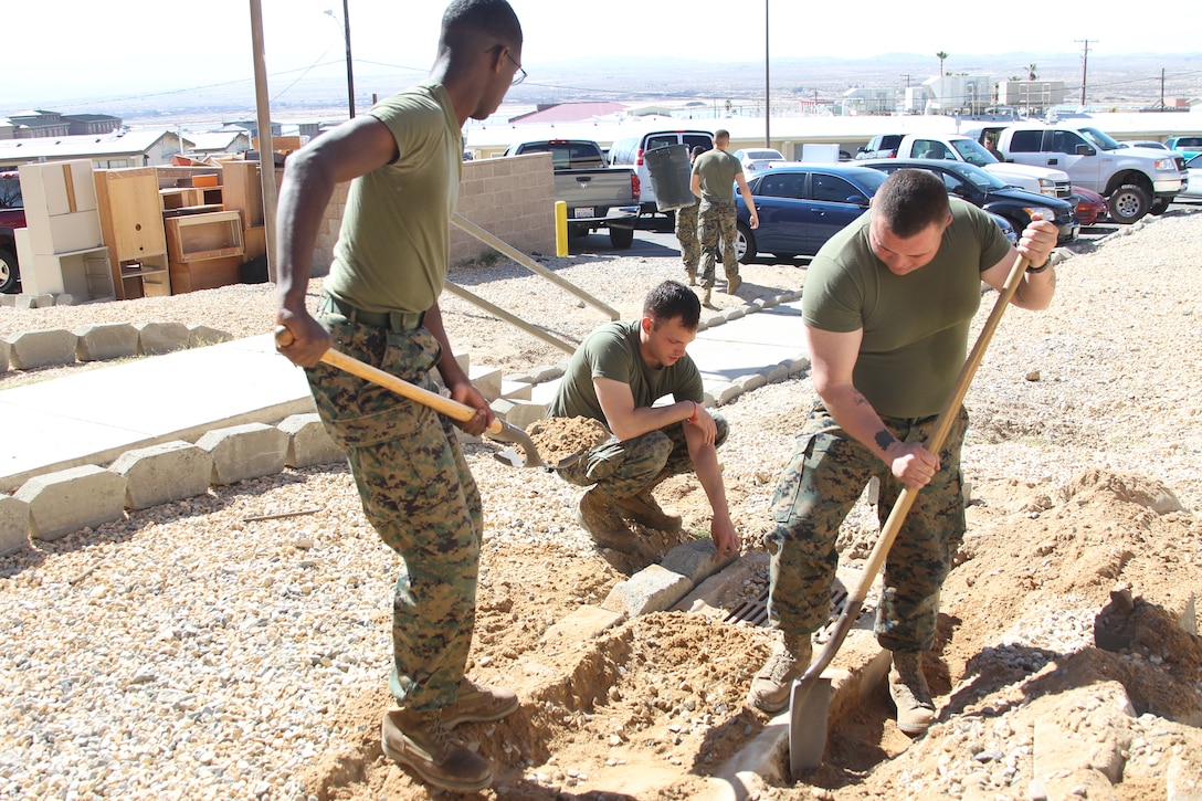 Marines dig alongside drainage pipes to place dresser stones during a working party at the Headquarters Battalion barracks Feb. 24, 2011.