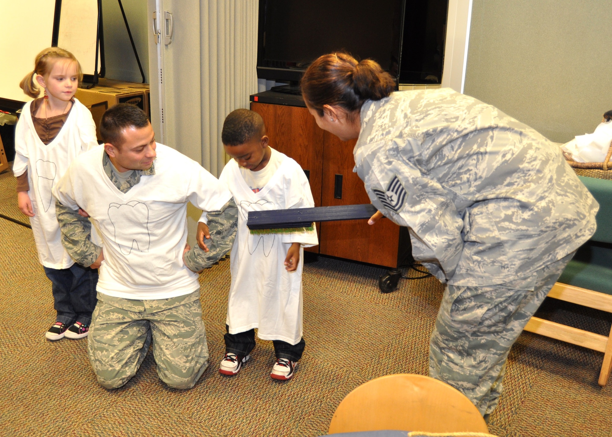 From left, Natalie Drummond, 8; Staff Sgt. Jacob Broersma, 81st DS; and Noble McGary, 5, learn how to brush “teeth” from Tech. Sgt. Caroline Bunce, an 81st DS dental hygienist, Feb. 9 at McBride Library.  Natalie’s parents are Tech. Sgt. Stephen and Rebecca Drummond, 85th Engineering Installation Squadron.  Noble’s mother is Capt. Janice McGary, 403rd Aeromedical Staging Squadron.  (U.S. Air Force photo by Steve Pivnick)