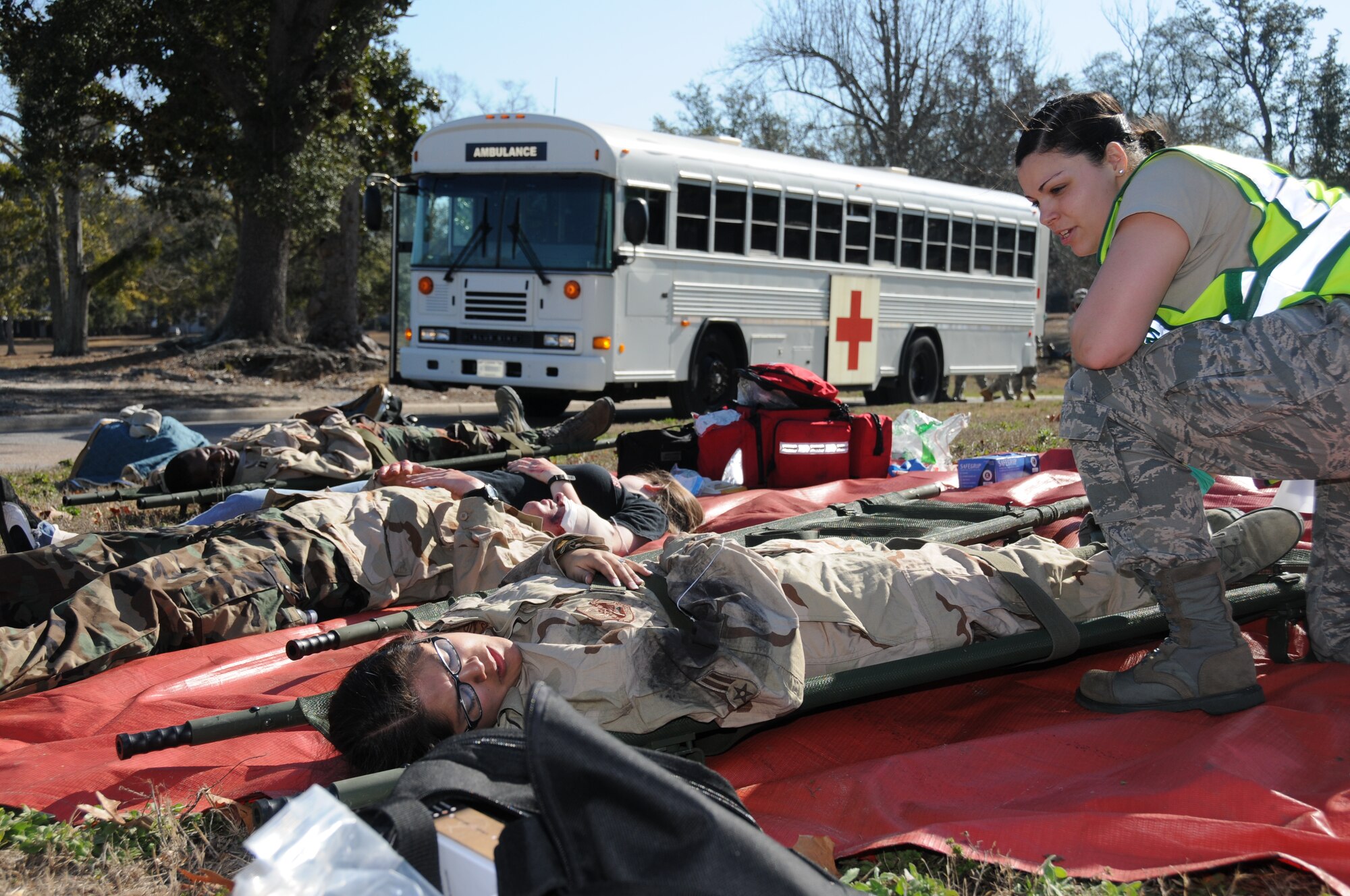 Airman 1st Class Ashley Figueroa, 81st Aerospace Medicine Squadron, checks on Airman 1st Class ShandaMoreno and other “victims” in the triage area during a major accident response exercise Feb. 17. Airman Moreno is a student in the 336thTraining Squadron. In the exercise scenario, two F-18s collide mid-air during an air show. The first plane crashes in Oak Park just north of the base, killing the pilot and injuring military and civilians in a primary parking area. The second plane went down into Biloxi’s Back Bay, but the pilot ejected and was rescued by the D’Iberville Fire Department.  (U.S. Air Force photo by Kemberly Groue)