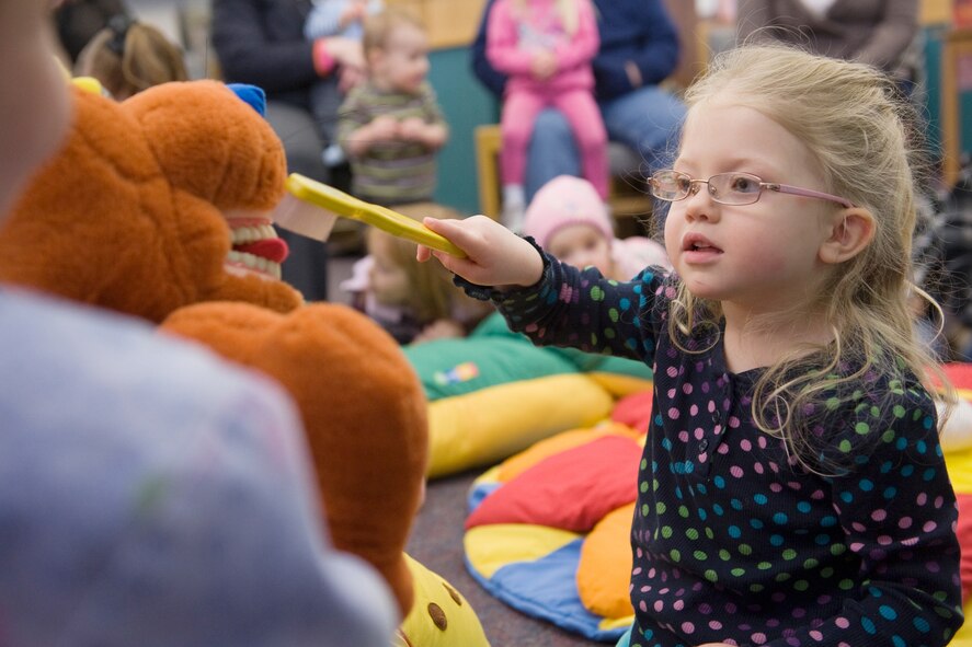 Little Warrior Emma, practices toothbrushing techniques on the stuffed kangaroo as part of a special Children's Dental Health Month presentation at the library's Preschool Story Hour Feb. 22. (U.S. Air Force photo/Beau Wade)
