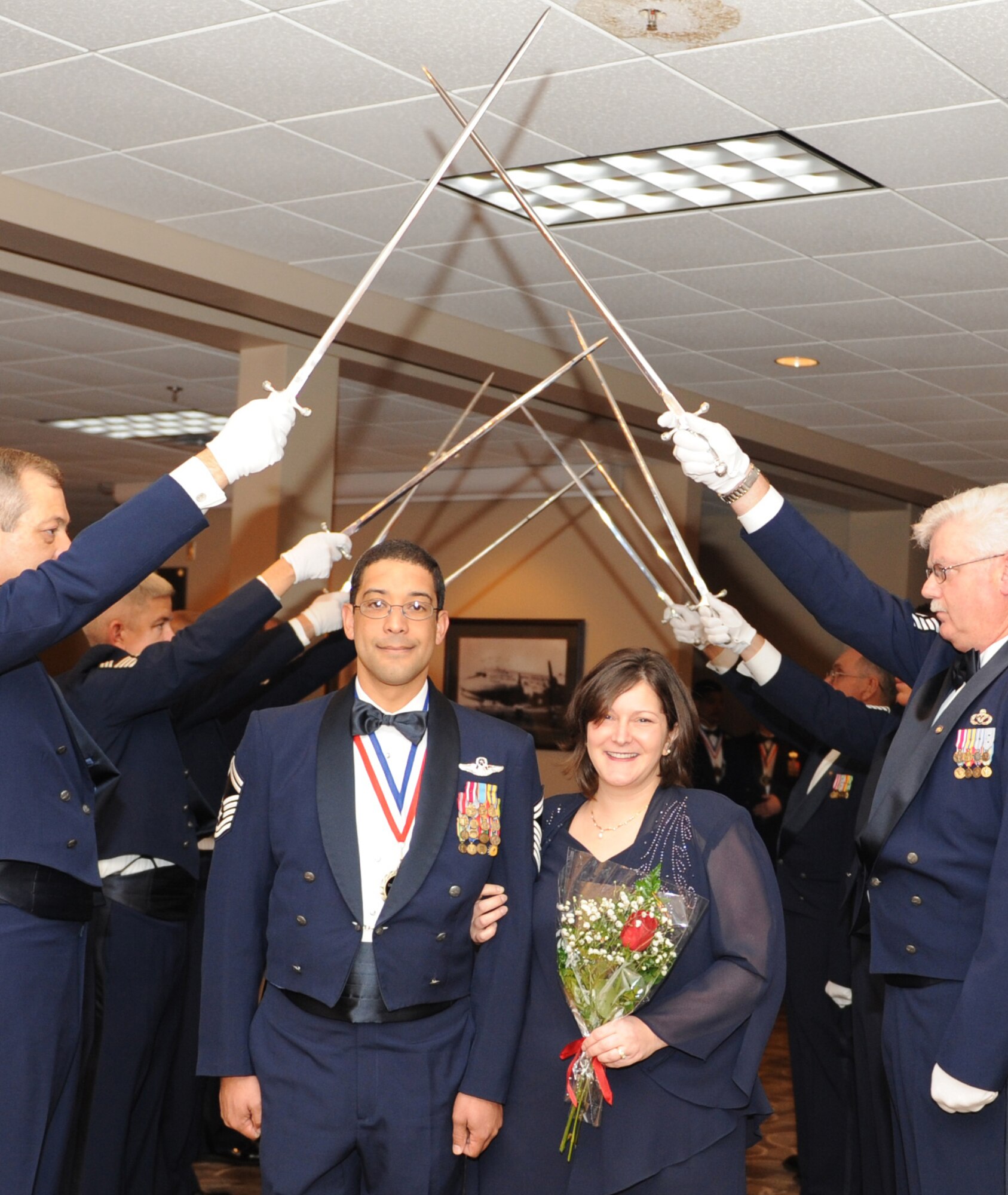 Senior Master Sgt. Thomas Gillard, a 314th Operations Group loadmaster functional manager, and wife, Cristina, walk under the sabers Feb. 18, 2011, during the Chief’s Induction Ceremony at Little Rock Air Force Base, Ark. Nine chiefs were inducted during the ceremony. (U.S. Air Force Photo by Airman 1st Class Ellora Stewart)
