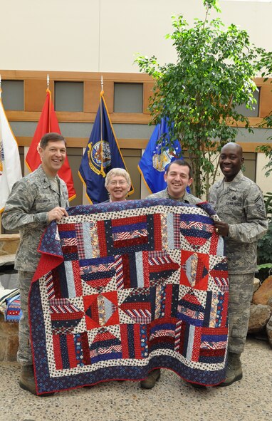 Col. Thomas C. Joyce, Air Force Mortuary Affairs Operations commander, Lenny Truitt, Quilts of Valor Foundation, Senior Airman Gregory Cody and Senior Master Sgt. Tyrone Williams, pose with a Quilt of Valor presented to Airman Cody for his service at the mortuary. Airman Cody is deployed from the 940th Memorial Affairs Squadron at Travis Air Force Base, Calif. (U.S. Air Force photo/Christin Michaud)

