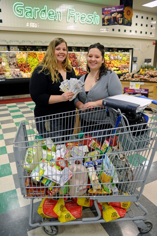 (Left) Mandy Morford and Whitney Burgett, Ellsworth Coupon Cutter page administrators, stand in front of a cart of groceries with a collection of coupons at the commissary at Ellsworth Air Force Base, S.D., Feb. 22, 2011.  They saved $88.75 on their groceries by using 77 coupons. (U.S. Air Force photo/Staff Sgt. Marc I. Lane)