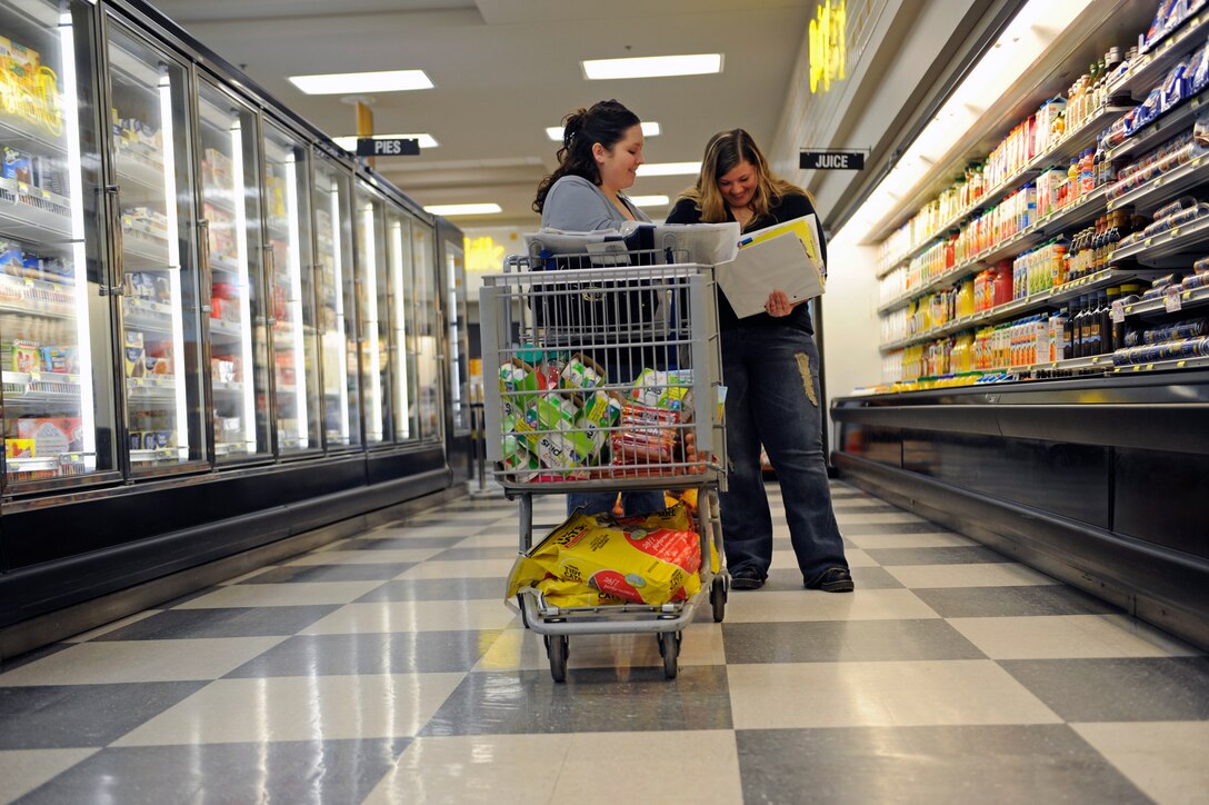 (Left) Whitney Burgett and Mandy Morford, Ellsworth Coupon Cutter page administrators, look through their binders of coupons to find savings on items as they shop at the commissary at Ellsworth Air Force Base, S.D., Feb. 22, 2011.  Couponing can help Airmen and their families to develop responsible good financial habits that will help them save money. (U.S. Air Force photo/Staff Sgt. Marc I. Lane)