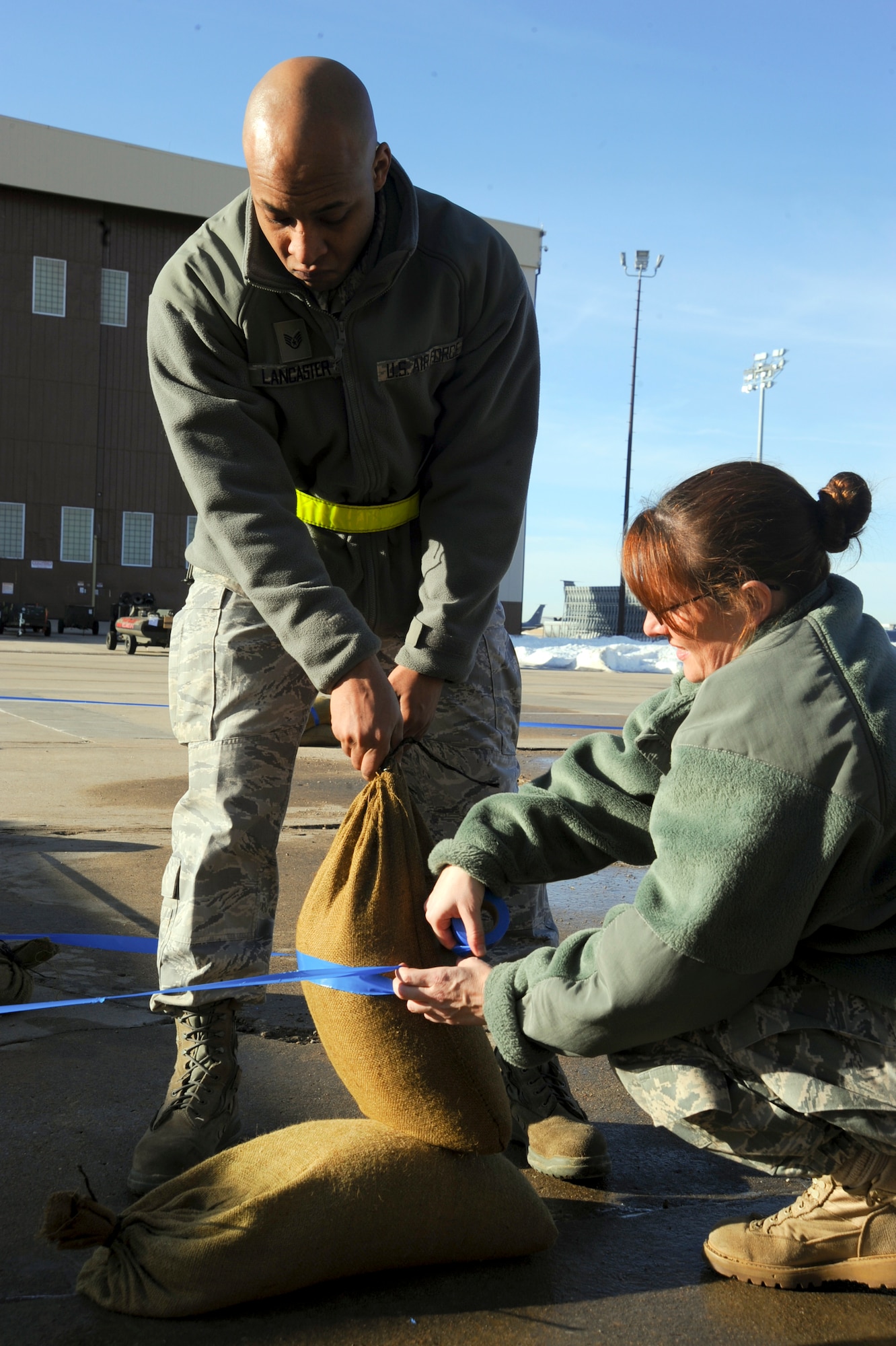 Staff Sgt. Marlon Lancaster, 22nd Force Support Squadron food service technician, and Tech. Sgt. Jamie Vancise, 22nd Communications Squadron knowledge operations section chief, build “bunker walls” during an operational readiness exercise, Feb. 14, 2011, McConnell Air Force Base, Kan.  The ORE prepared McConnell’s Airmen by training them to deal with real-world emergency situations during expeditionary deployments.  (U.S. Air Force photo/Staff Sgt. Dallas Edwards)
