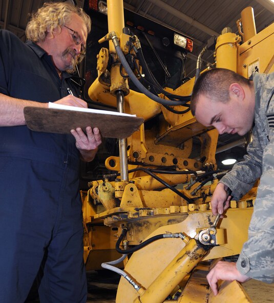 Claire Morseth, 319th Logistics Readiness Squadron heavy mobile equipment mechanical supervisor, oversees maintenance to a Champion road grader by Staff Sgt. Dustin Withrow, 319th LRS. Morseth is the Warrior of the Week for Feb. 24 through March 1. Warrior of the Week recognizes everyday Airmen, working their every day jobs. (U.S. Air Force photo by Airman 1st Class Amber Bennett)