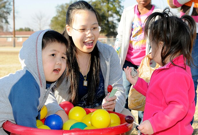 Three-year-old Thanadit (left) and two-year-old Narida Kemenkul search for rocks during the game ‘Hitting Rock Bottom’ with their mother, Suerjee Lee, during the annual Learn and Earn Carnival Feb. 23. The event had children digging to the bottom of the bucket in search for a special rock; once it was found a number on the rock would indicate how much play money they had earned. (U.S. Navy photo/Mass Communication Specialist 1st Class Jennifer Hudson)