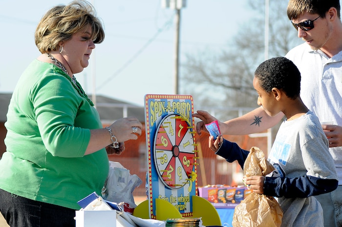 Nine-year-old Jermaine Mitchell receives his prize candy from Kim Brown, a financial specialist at the Fleet and Family Support Center, after spinning the ‘Spin-a-Prize’ wheel during the annual Learn and Earn Carnival at Menriv Soccer Field at Joint Base Charleston-Weapons Station, Feb. 23. The event was held in conjunction with Military Saves Week and is designed to teach children money management and savings through fun interactive games. (U.S. Navy photo/Mass Communication Specialist 1st Class Jennifer Hudson)
