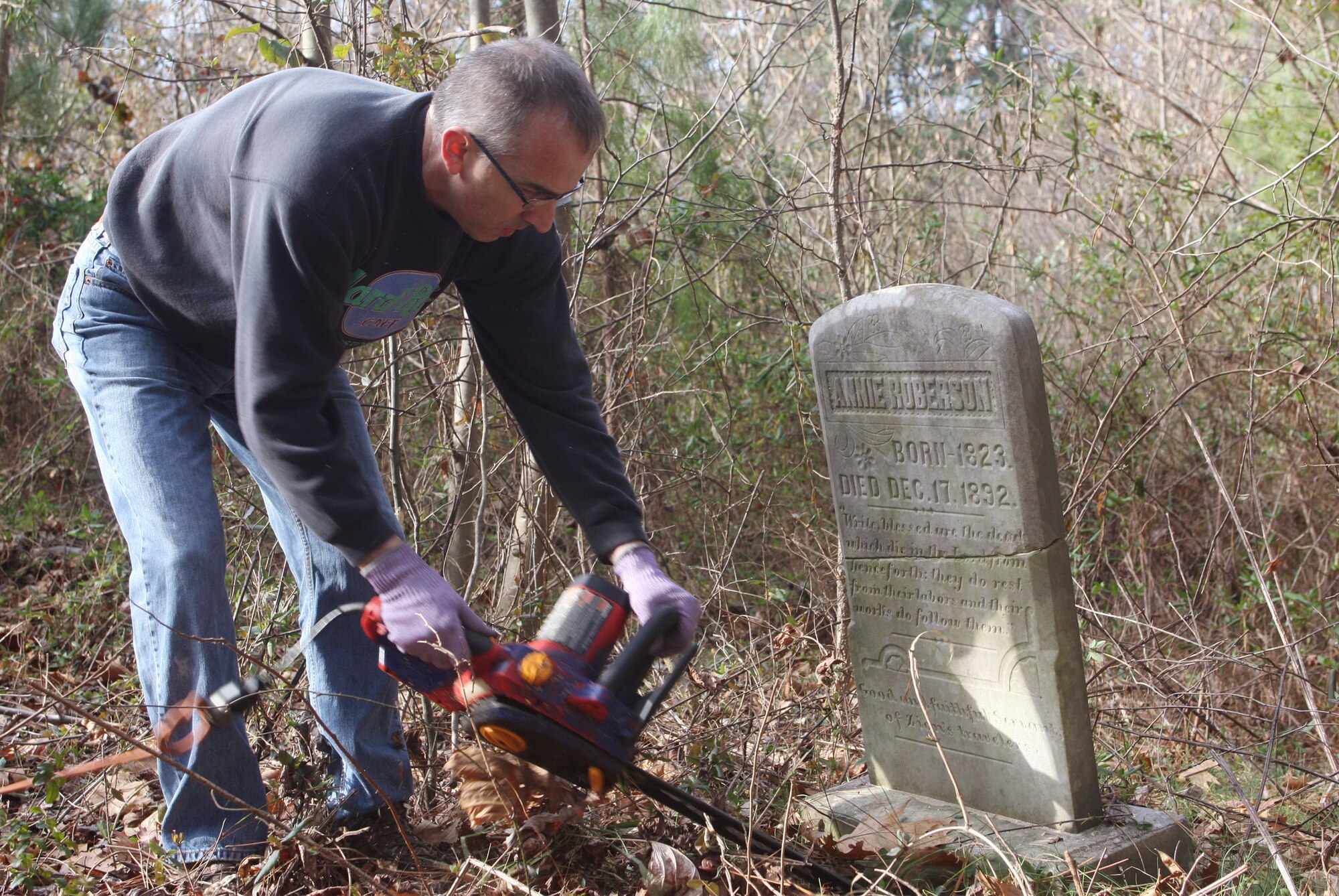 Capt. Frank Pascarelli, from the 94th Aeromedical Evacuation Squadron, clears around one of the grave markers in the Jonesville Cemetery located on base. Capt. Pascarelli was one of the groups of volunteers from Dobbins who worked to clear overgrowth Feb. 19. (U.S. Air Force photo/Don Peek)