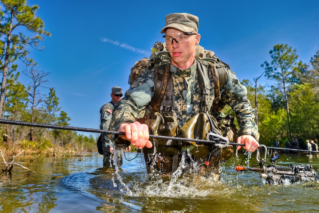 A U.S. Army Ranger student pulls himself and his combat gear from the water during the rope bridge, small boat and swamp training at Camp Rudder on Eglin Air Force Base, Fla., Feb. 15, 2011.
