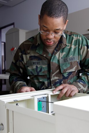 Seabee Seaman Anthony West, construction electronic construction man and station locksmith, fixes the lock to a safe at the station air terminal here Feb. 25. 22-year-old West is the youngest Seabee aboard the air station.