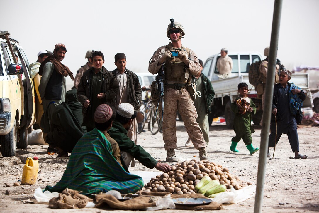 Lance Cpl. Christopher Willis, a Squad Automatic Weapon gunner with Golf Company, 2nd Battalion, 3rd Marine Regiment, snaps pictures of merchants at Khalaj Bazaar, Garmsir District, Helmand province, Afghanistan, on “Bazaar Friday,” Feb. 25. On Fridays, Khalaj Bazaar draws an average of about 3,000 villagers who gather to buy and sell livestock, meat, poultry, textiles, and various wares. The bazaar draws traders from as far as Herat province, in Western Afghanistan.