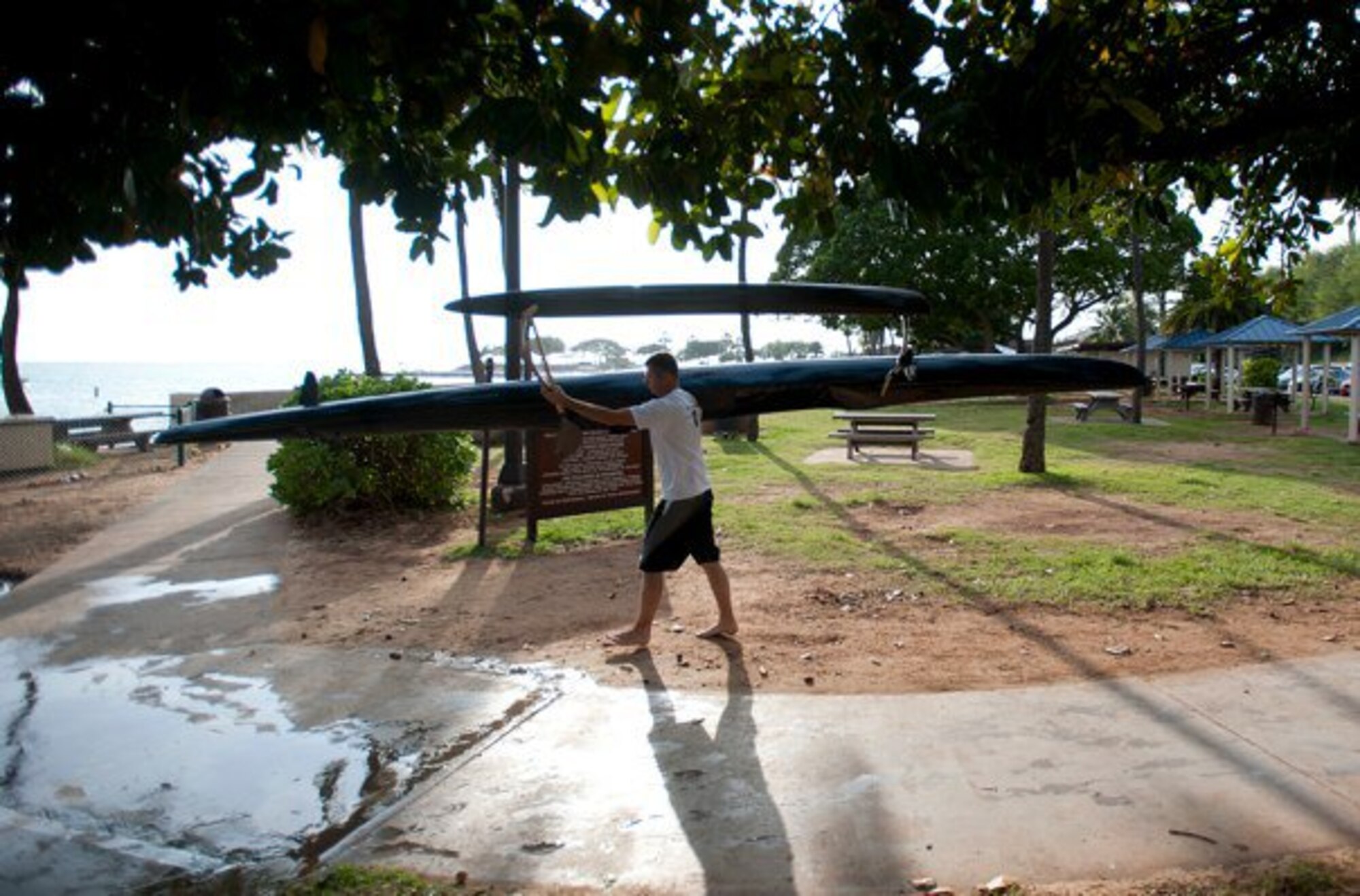 Master Sgt. Jeff Allen, a strategic plans technician with the Pacific  Air Forces public affairs office at Joint Base Pearl Harbor Hickam, carries his canoe toward Hickam Beach Feb. 17. "Paddling" is a popular local pastime in which paddlers brave the Pacific Ocean in outrigger canoes ranging in size from one to six passengers. (U.S. Air Force photo by Staff Sgt. Nathan Allen)