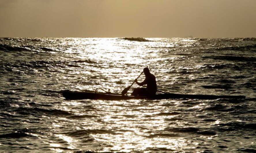 Master Sgt. Jeff Allen, a strategic plans technician with the Pacific  Air Forces public affairs office at Joint Base Pearl Harbor Hickam, paddles a canoe underneath the glow of the setting sun at Hickam Beach Feb. 17. "Paddling" is a popular local pastime in which paddlers brave the Pacific Ocean in outrigger canoes ranging in size from one to six passengers. (U.S. Air Force photo by Staff Sgt. Nathan Allen)