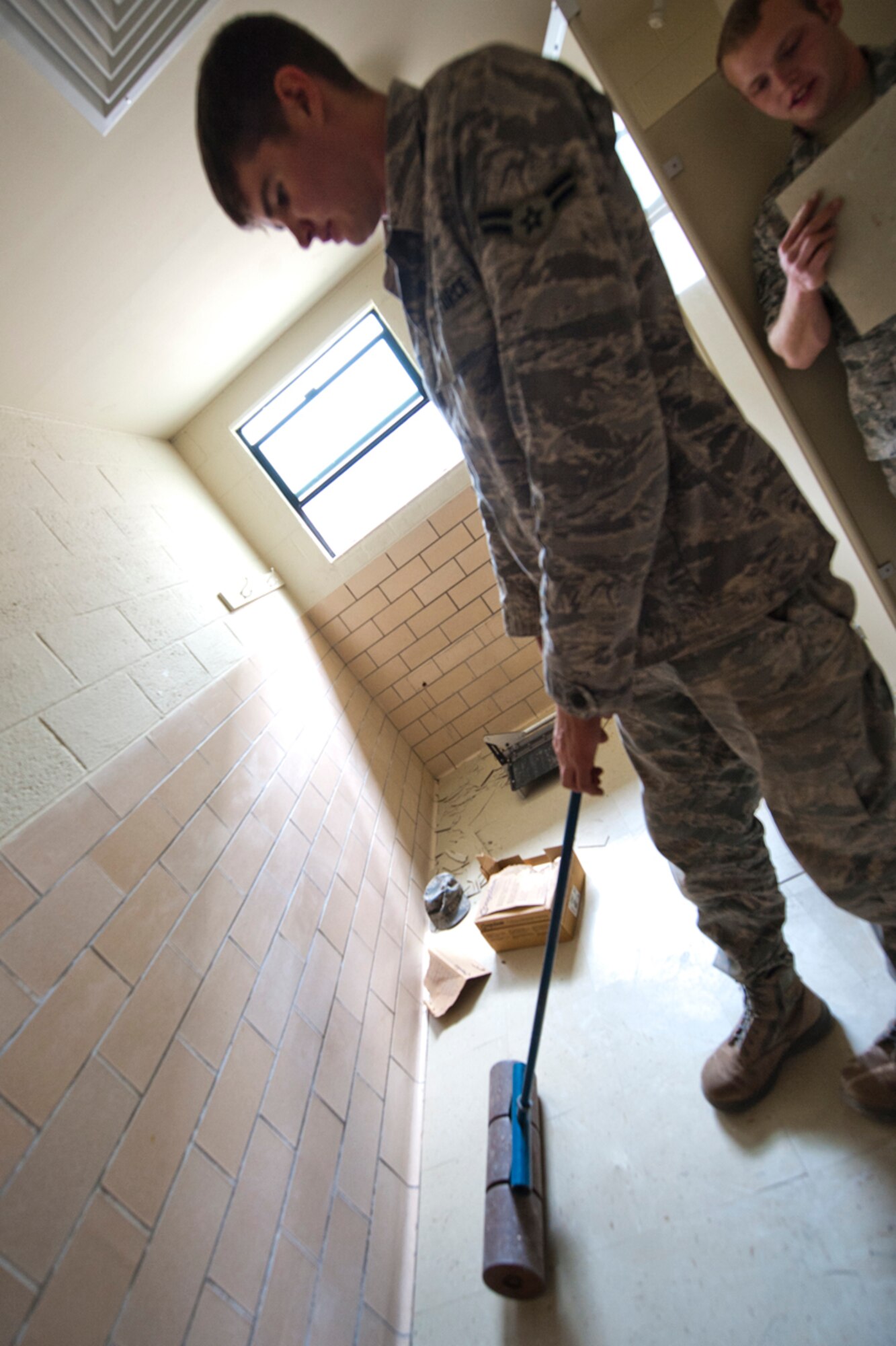 HOLLOMAN AIR FORCE BASE, N.M. -- Airman 1st Class Tyler Huisken, 49th Civil Engineer Squadron, uses a floor roller to level the newly-installed tiles at the 746th Test Squadron facility Feb. 18, 2011. Members of the 49th CES responded to and repaired more than $3 million in damages caused by a record-breaking February snow storm. Because of all the water breaks, water usage on base soared. In addition to the water problems, the base, much like the rest of the state, had complications with it's gas. (U.S. Air Force photo by Senior Airman Veronica Stamps/ Released)