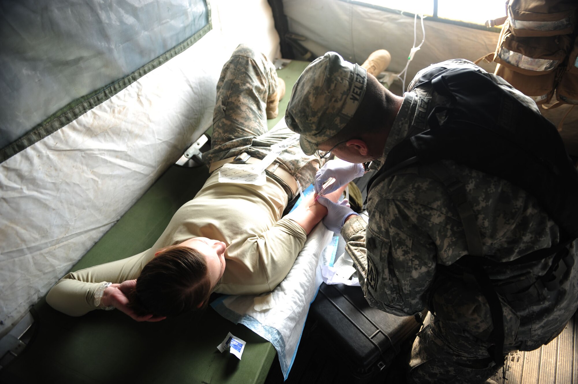CALIENTE, Nev. -- Sgt. Henry Velez, healthcare specialist, administers intravenous fluids to Spc. Tana Baker, Patriot fire control enhanced operator during Operation Red Flag 11-3 Feb. 24. Velez is training to maintain proficiency in the administration of medical care under field conditions. Red Flag is a realistic combat training exercise that provides heavily-contested and degraded operational environments to prepare crews for major combat operations against a near-peer adversary. (U.S. Air Force photo by 2nd Lt. Tony Richardson) (Released)