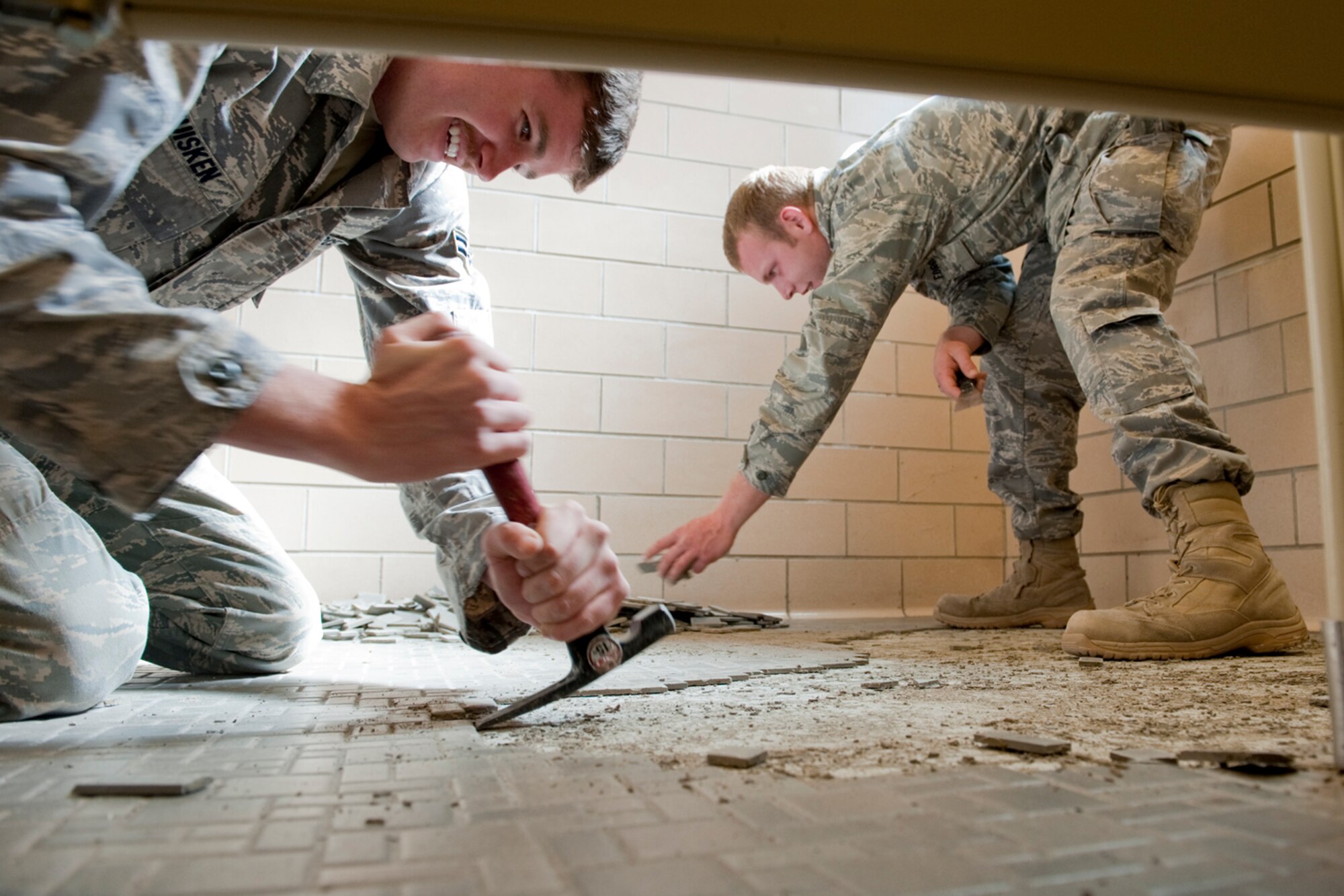 HOLLOMAN AIR FORCE BASE, N.M. -- Airmen 1st Class Tyler Huisken and Benjamin Brady, both members of the 49th Civil Engineer Squadron, remove tile at the 746th Test Squadron facility Feb. 16, 2011. Members of the 49th CES responded to and repaired more than $3 million in damages caused by a record-breaking February snow storm. There were 145 buildings in the industrial area of the base that suffered damage from freezing. (U.S. Air Force photo by Senior Airman Veronica Stamps/ Released)
