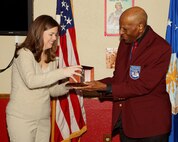 Dr. Granville Coggs, a former Tuskegee Airman, hands Tami Cook the 37th Training Wing Key Spouse of the Year Award during the 323rd Training Squadron commander's call Feb. 14. Mrs. Cook is also the 37th TRW nominee for the Joan Orr Spouse of the Year Award. (U.S. Air Force photo/Antonio Morano)
